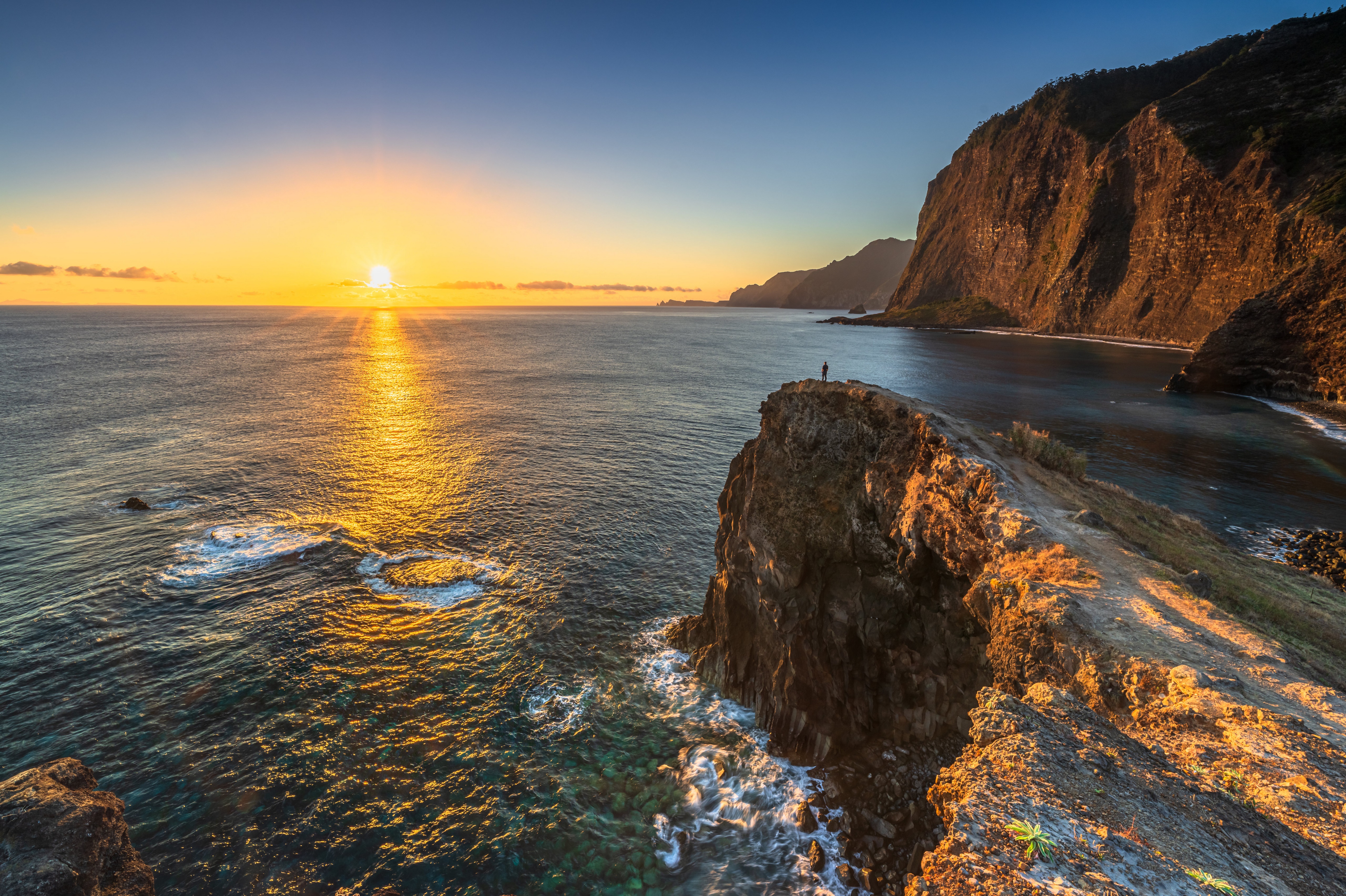 Sunset over Madeira coast with a lone figure on a cliff HD Wallpaper