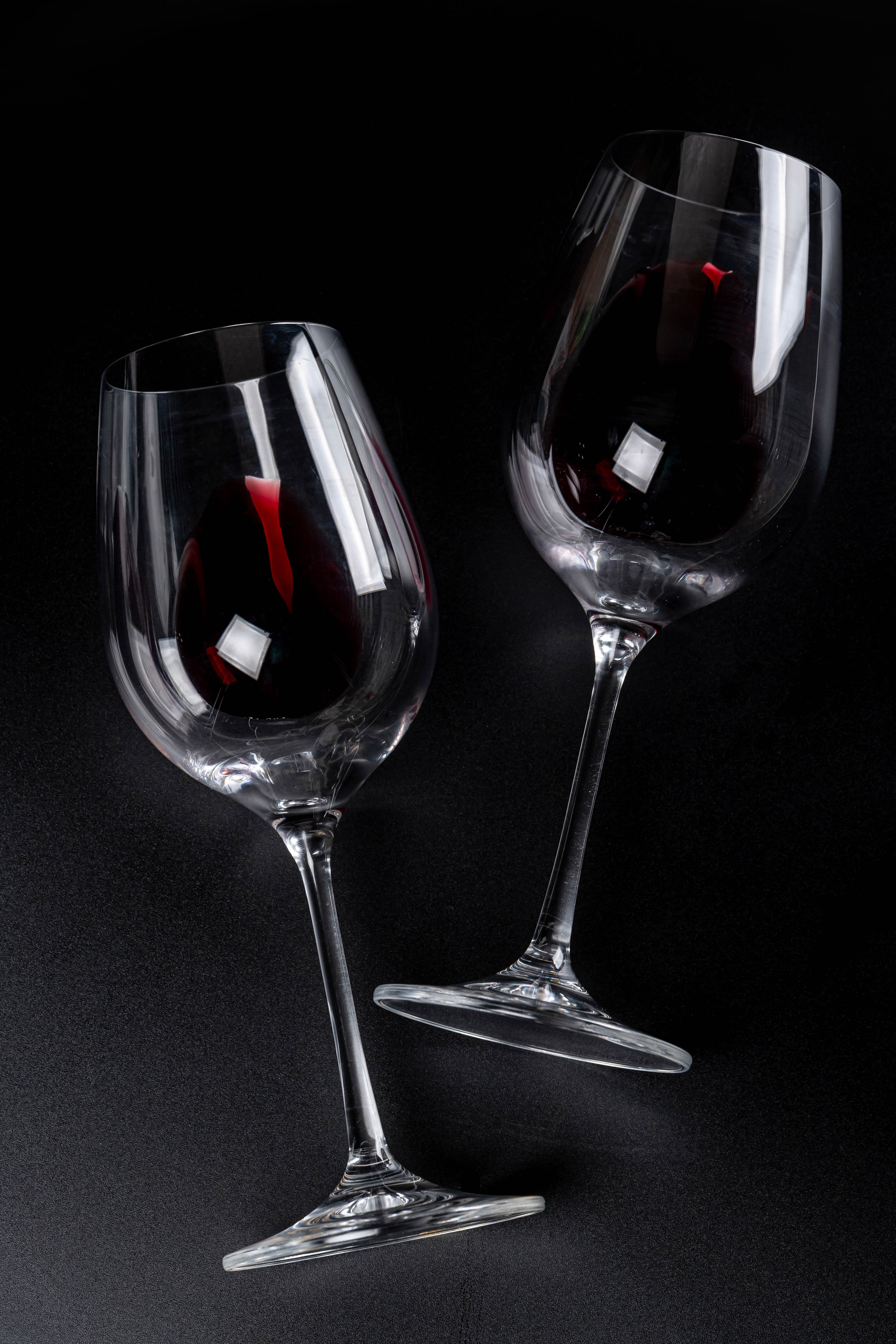 Two wine glasses filled with red wine on a black background HD Phone Wallpaper