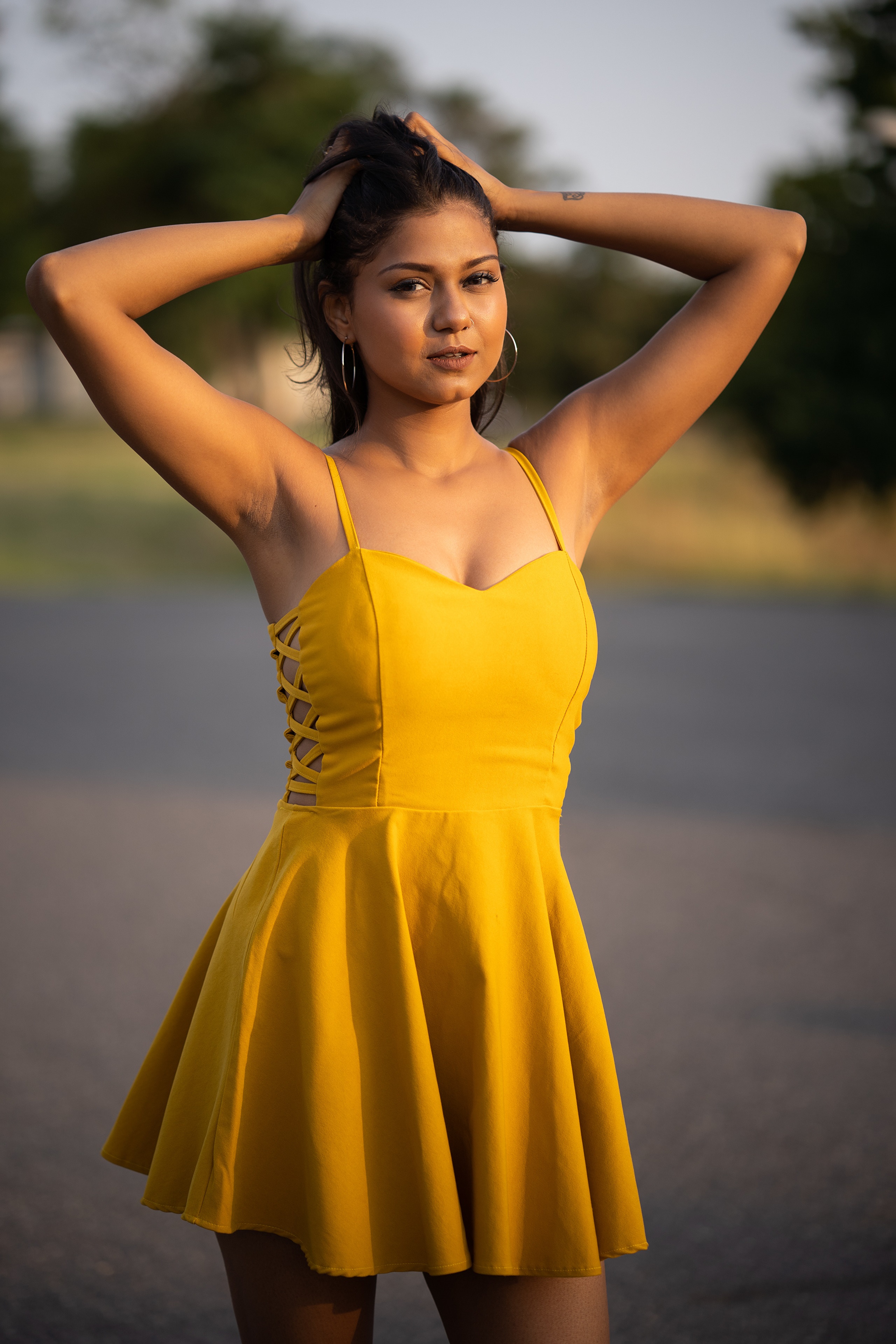 Brunette girl in yellow dress with hands in hair HD Phone Wallpaper