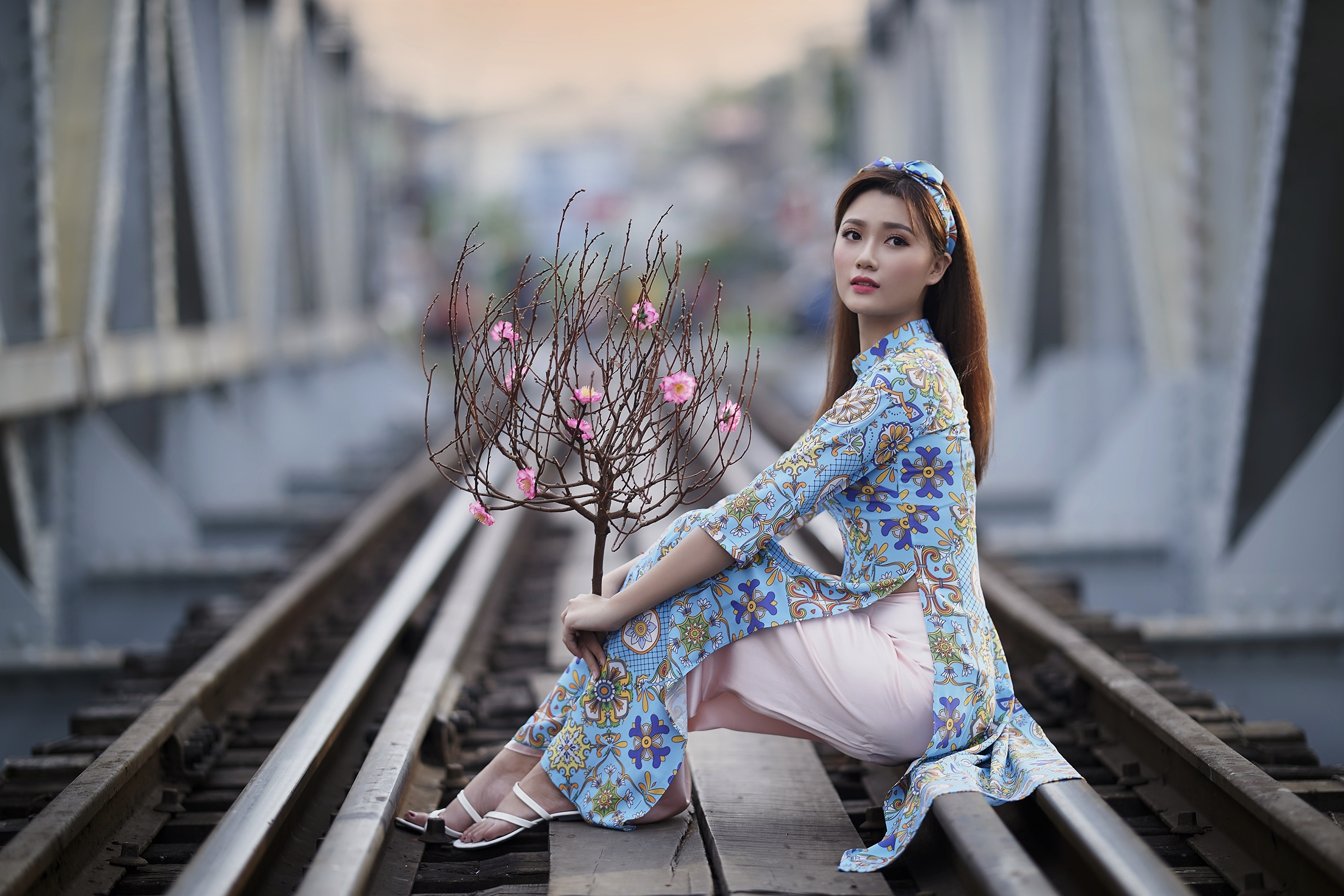 Asian woman in traditional dress on train tracks with branches HD Wallpaper