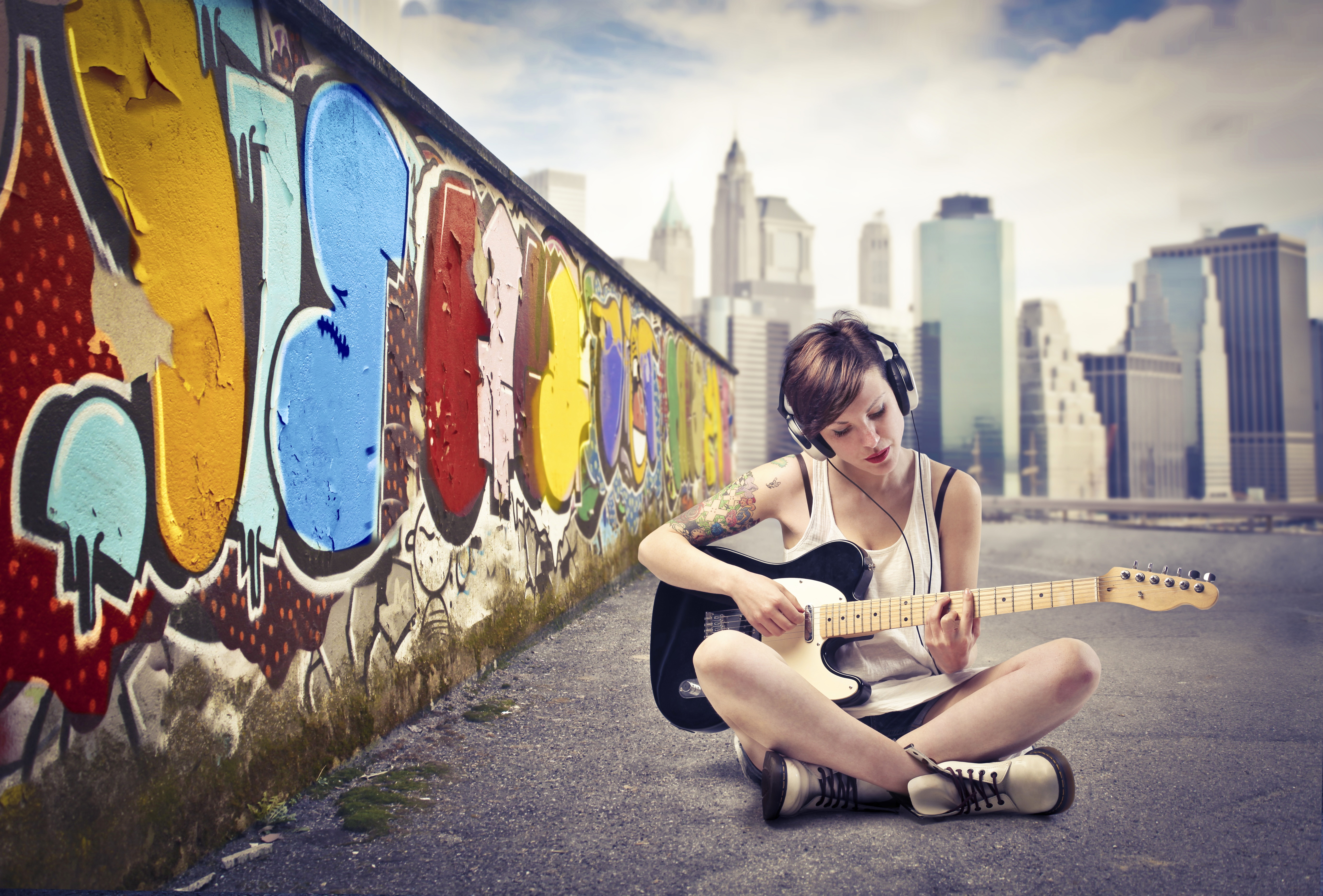 Girl with headphones playing guitar near graffiti wall HD Wallpaper