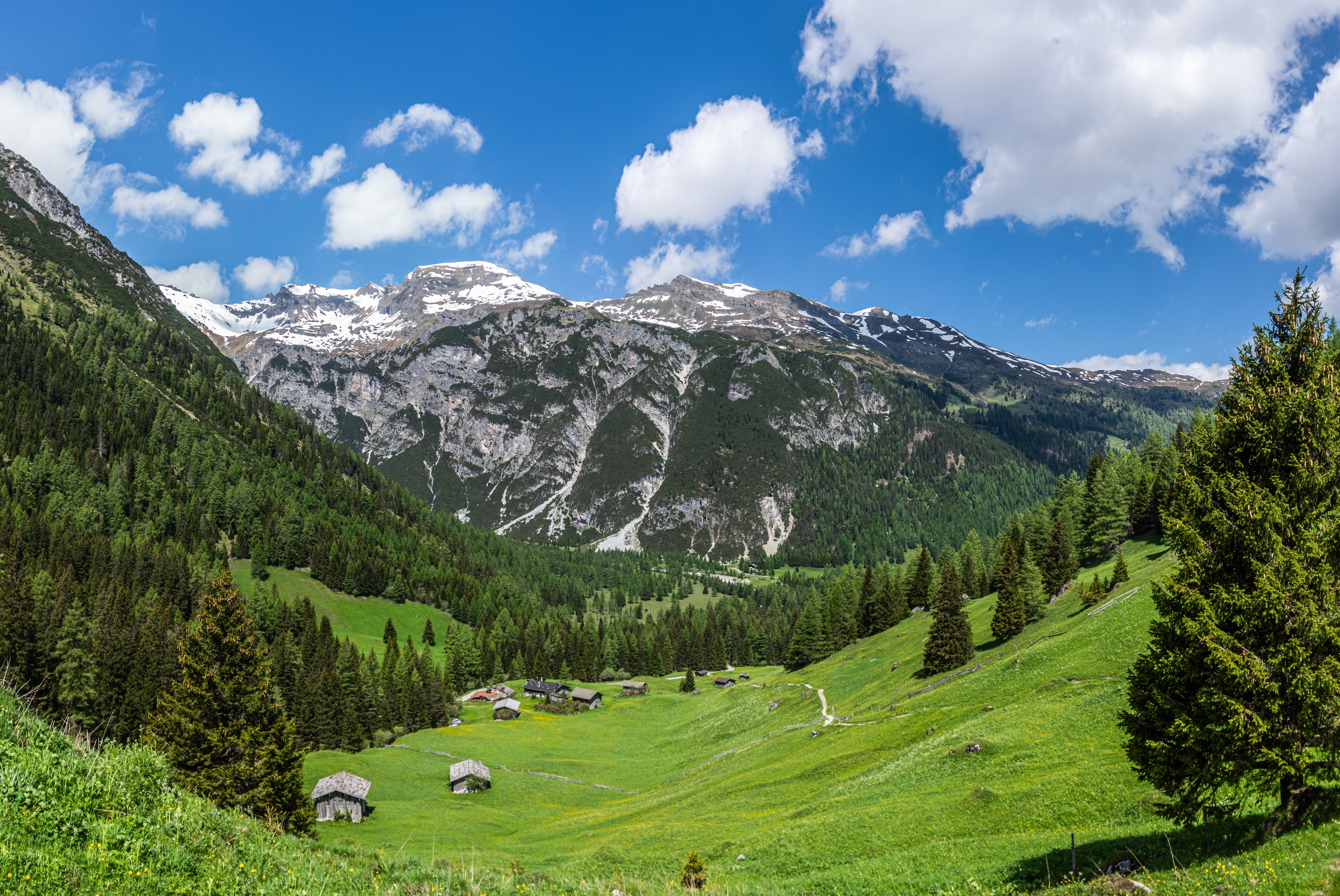 Alpine valley with houses and snow-capped mountains in Austria HD Wallpaper