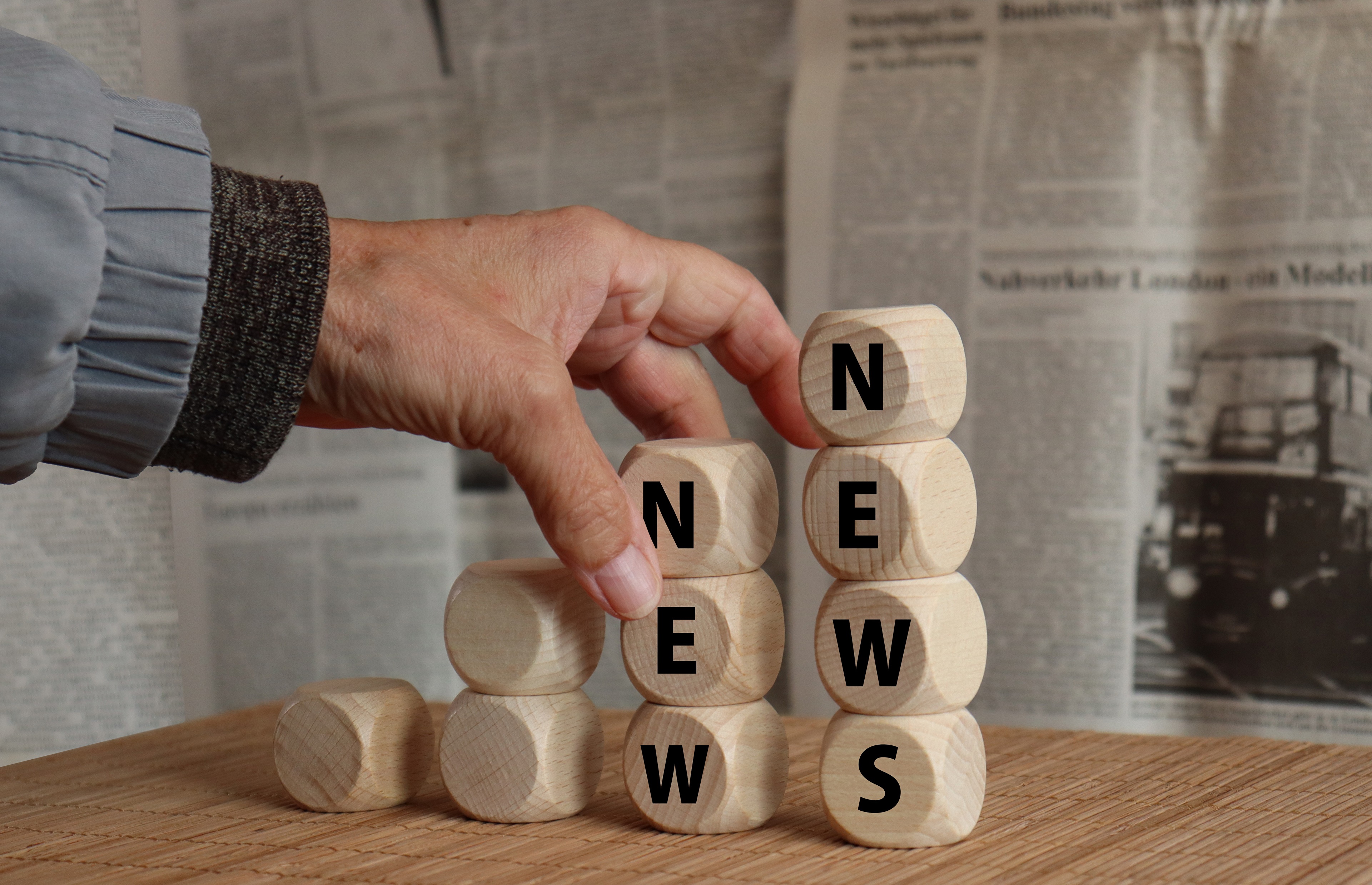 Hand stacking wooden blocks spelling NEWS HD Wallpaper