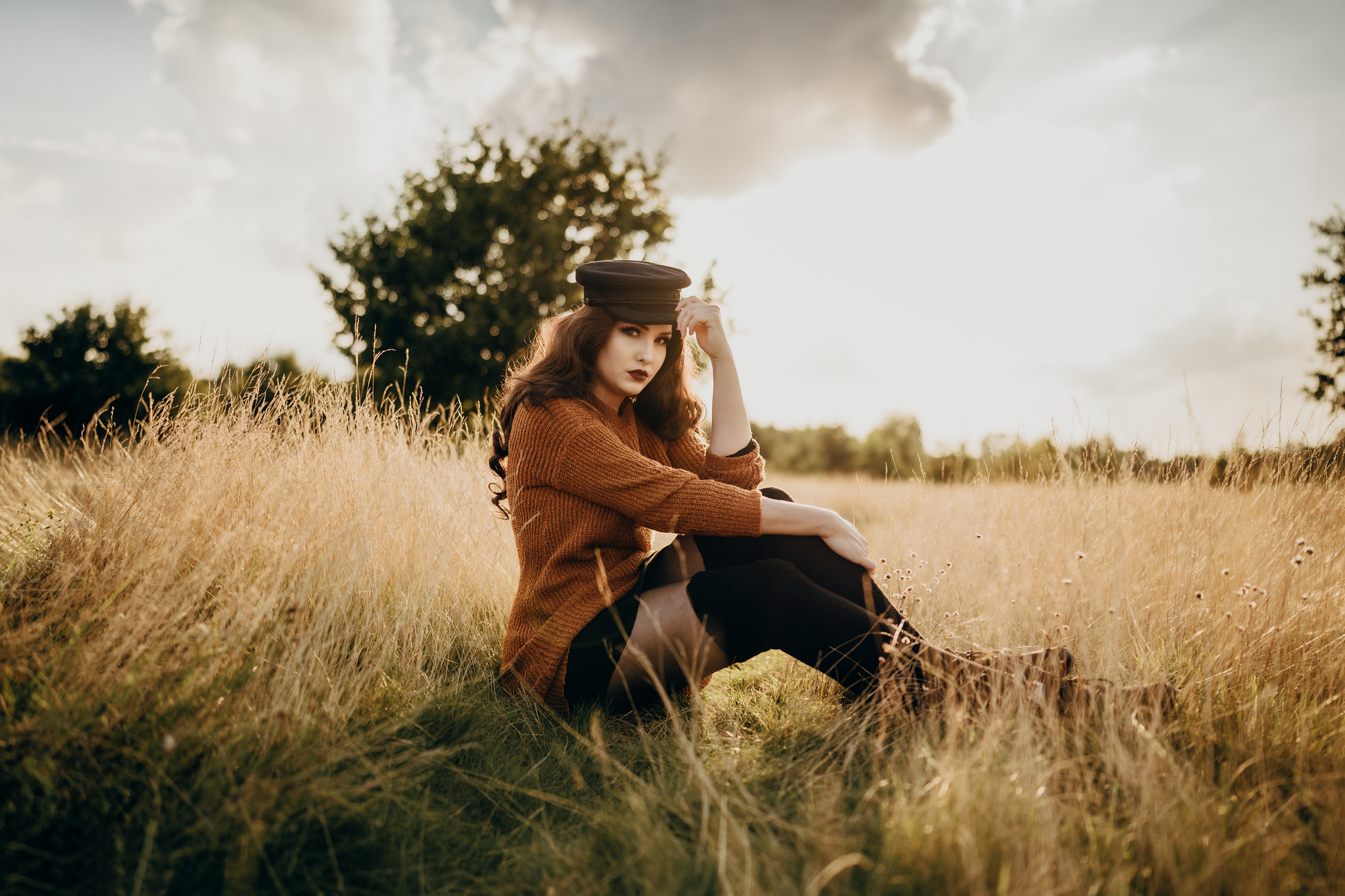 Virginia Hinz in a sweater and baseball cap in a field HD Wallpaper