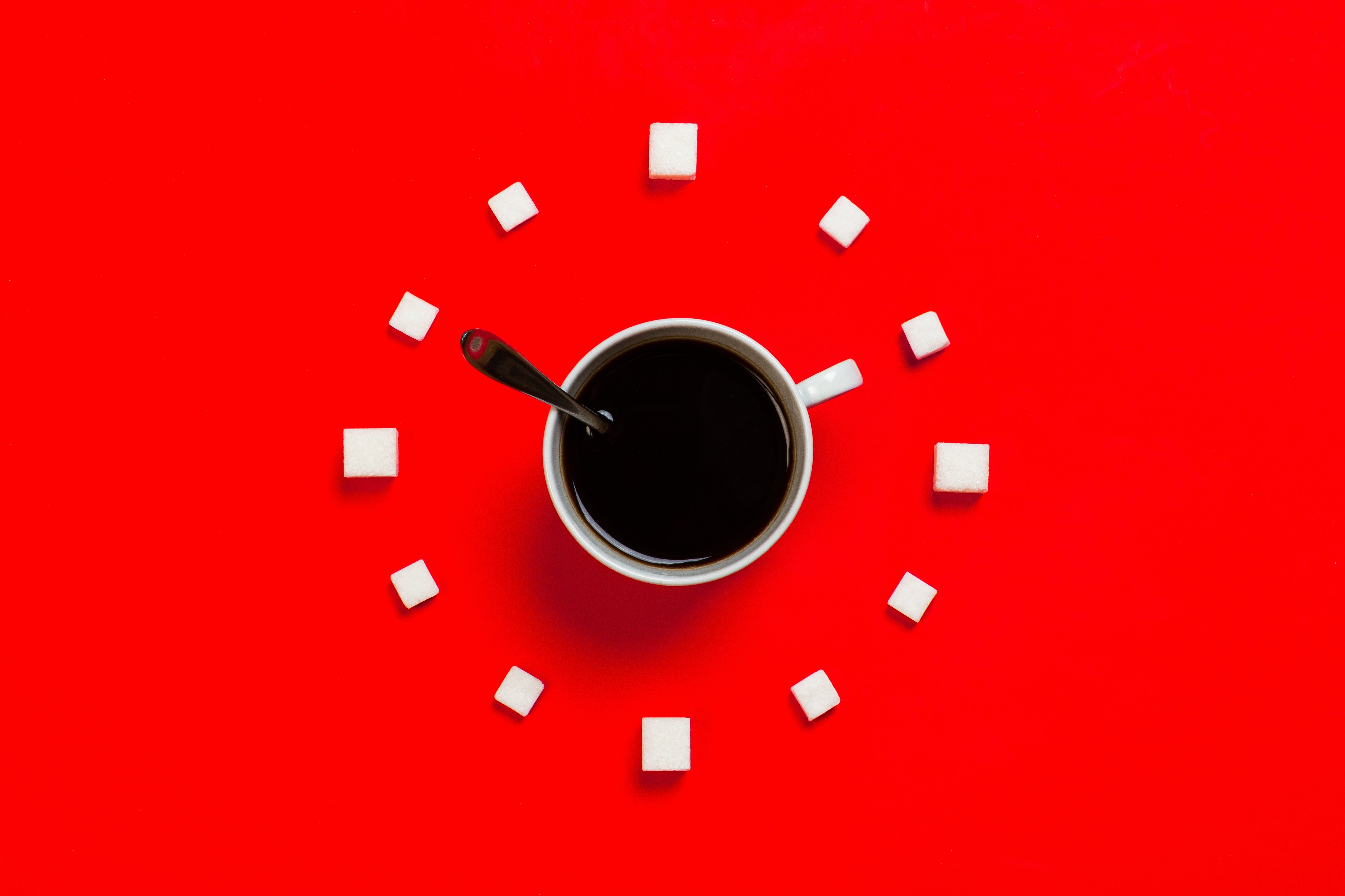 Coffee cup and sugar cubes arranged like a clock on a red background HD Wallpaper