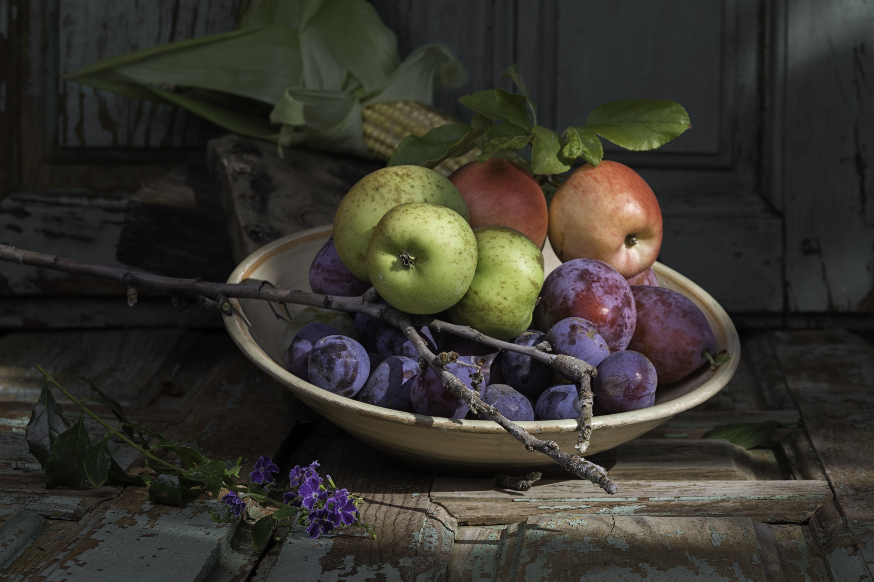 Still life of apples, plums, and corn on a wooden table HD Wallpaper