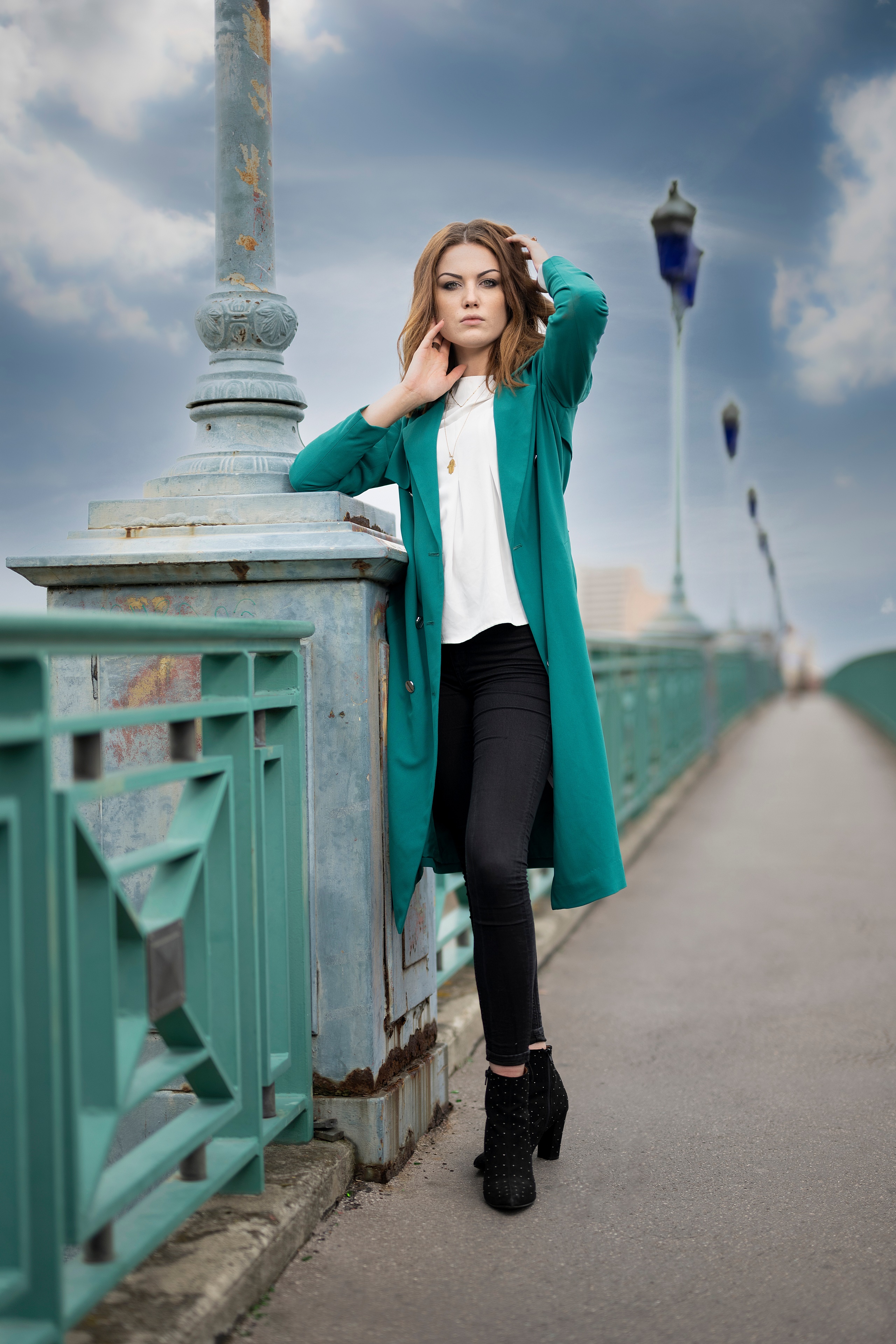 Woman in teal coat posing on a bridge HD Phone Wallpaper