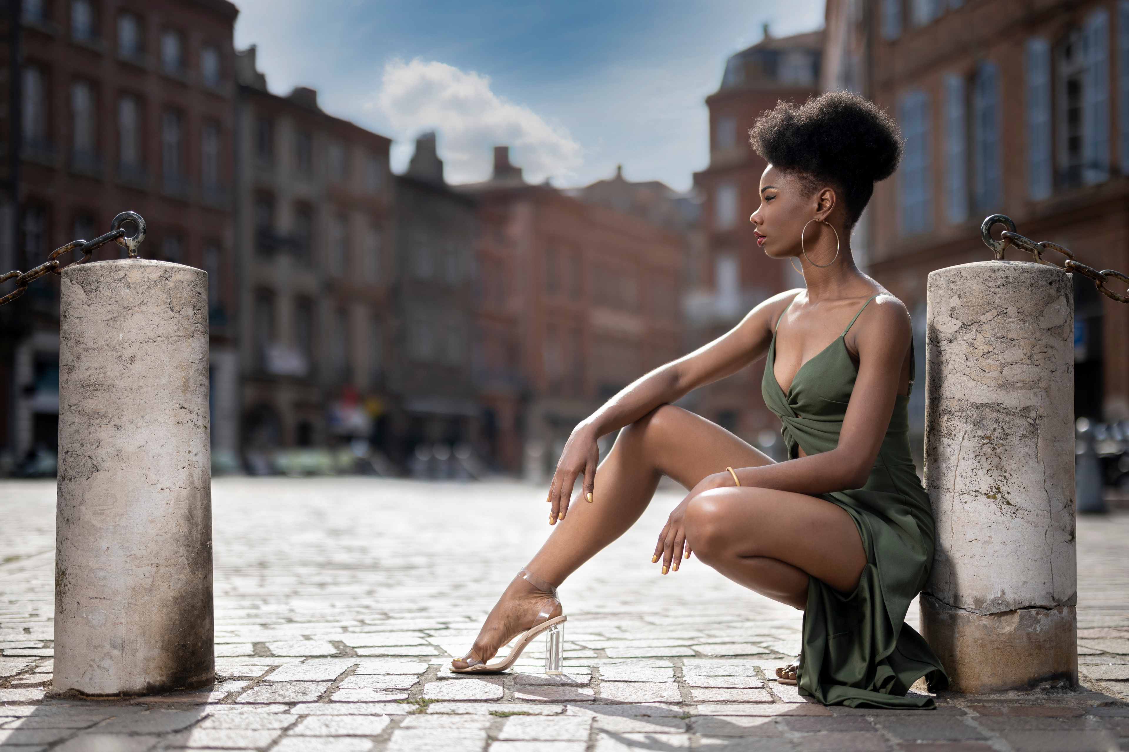 Woman in green dress posing in city square HD Wallpaper