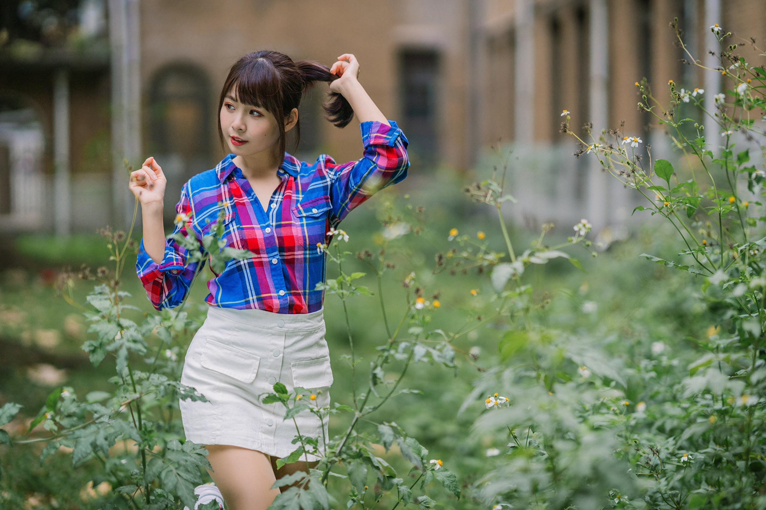 Asian woman in plaid shirt and white skirt posing outdoors HD Wallpaper