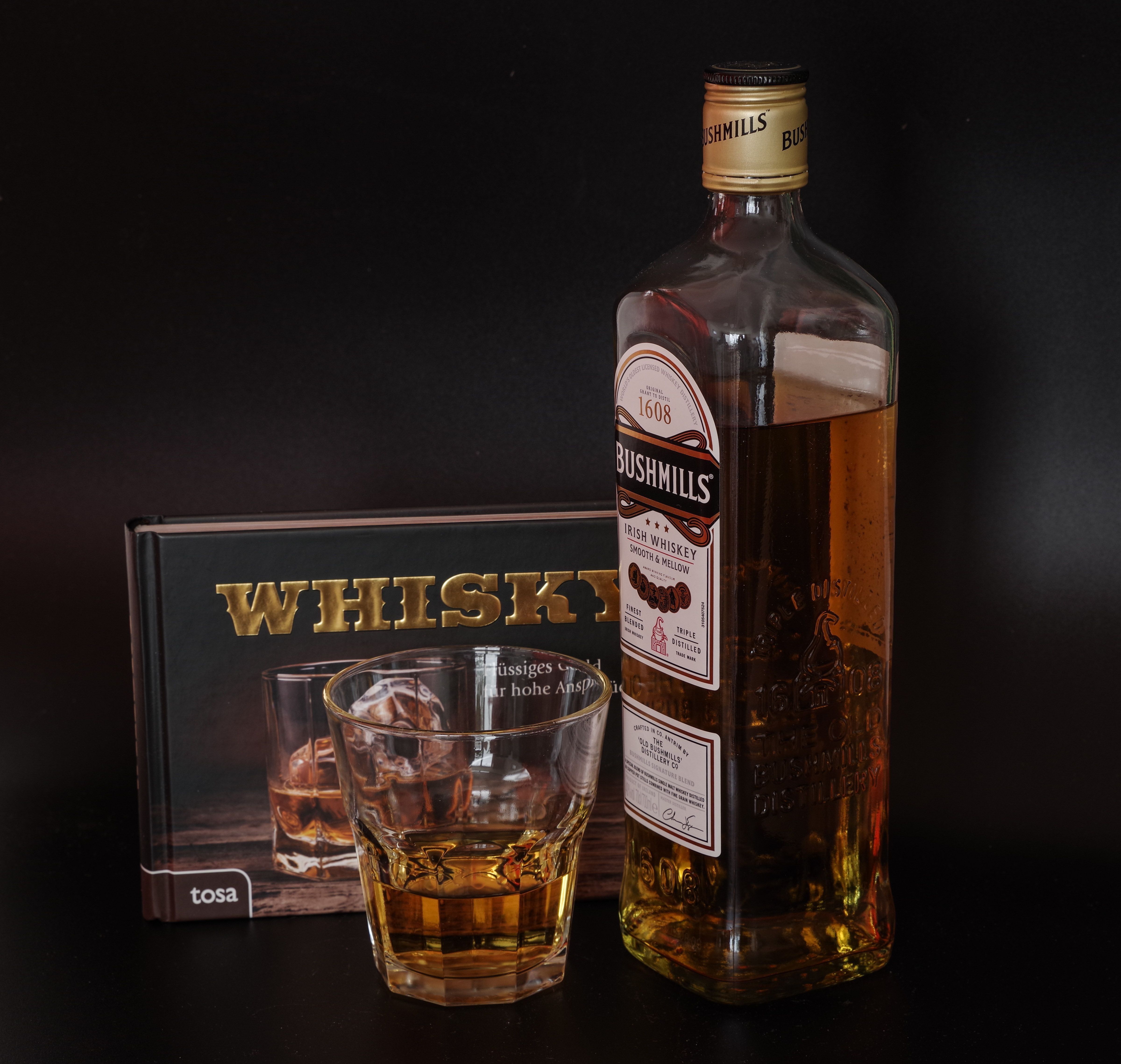 Bushmills Irish Whiskey bottle and glass with book HD Wallpaper