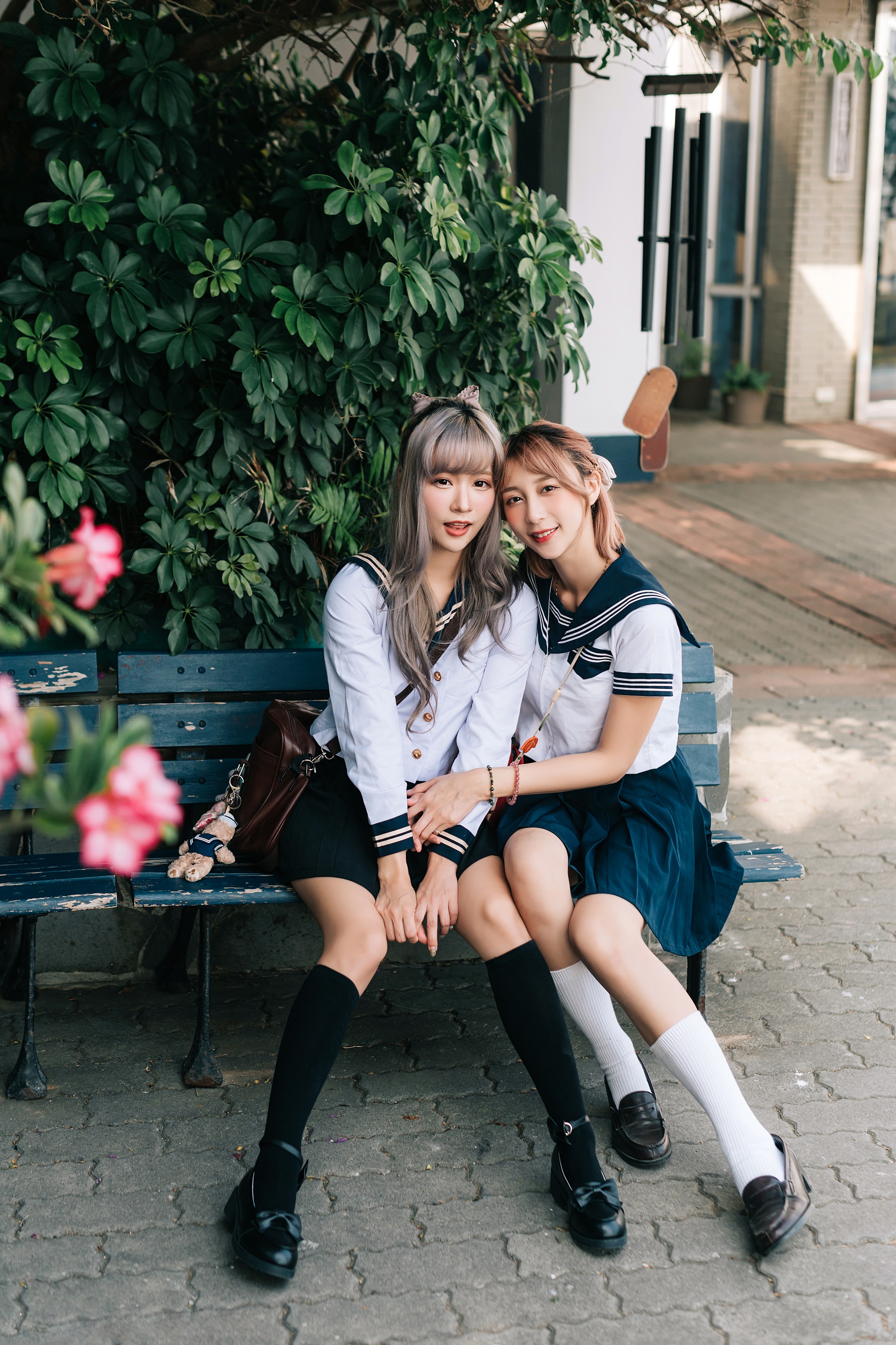 Two Asian schoolgirls in uniform sitting on a bench HD Phone Wallpaper