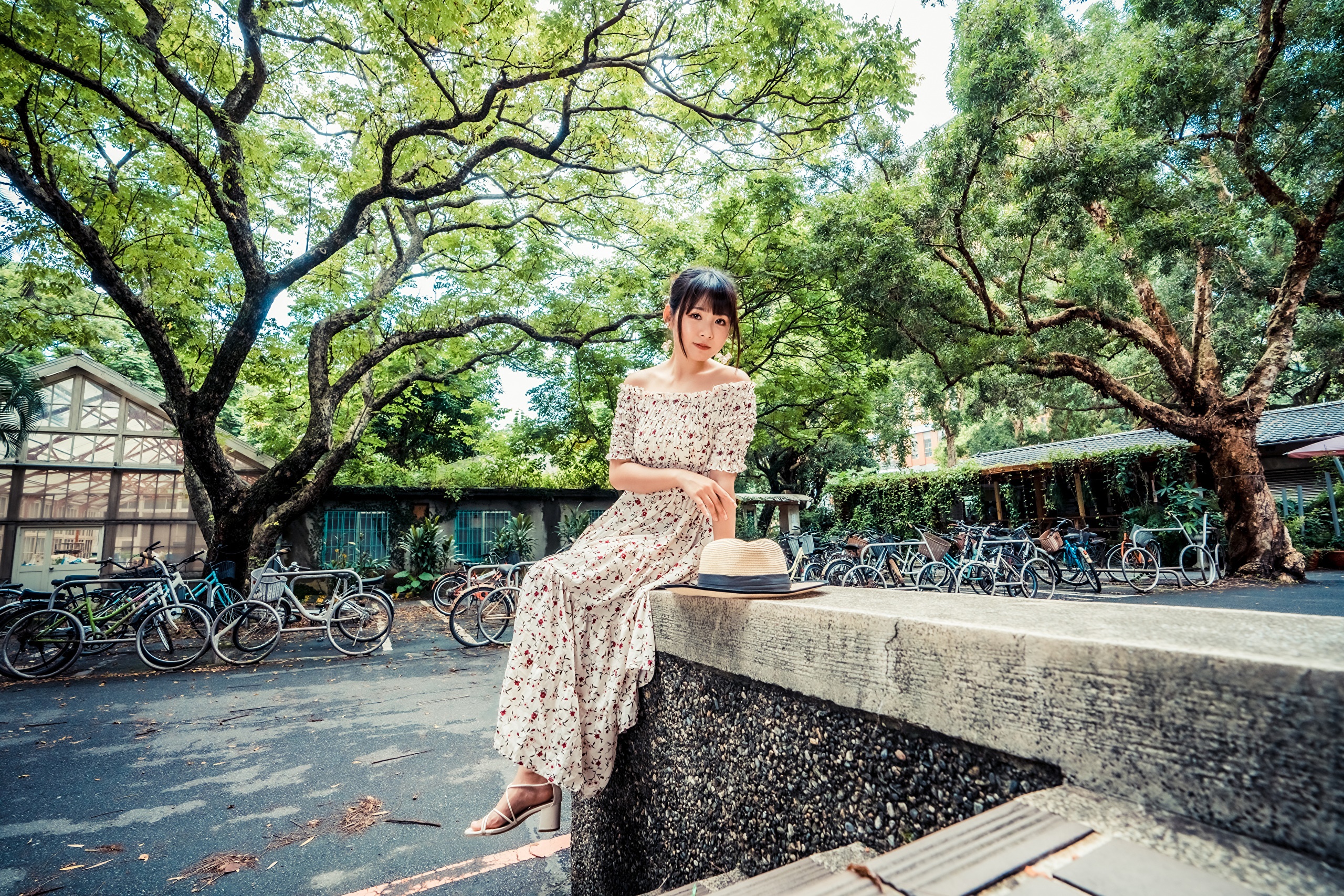 Asian woman in floral dress sitting on wall with hat HD Wallpaper