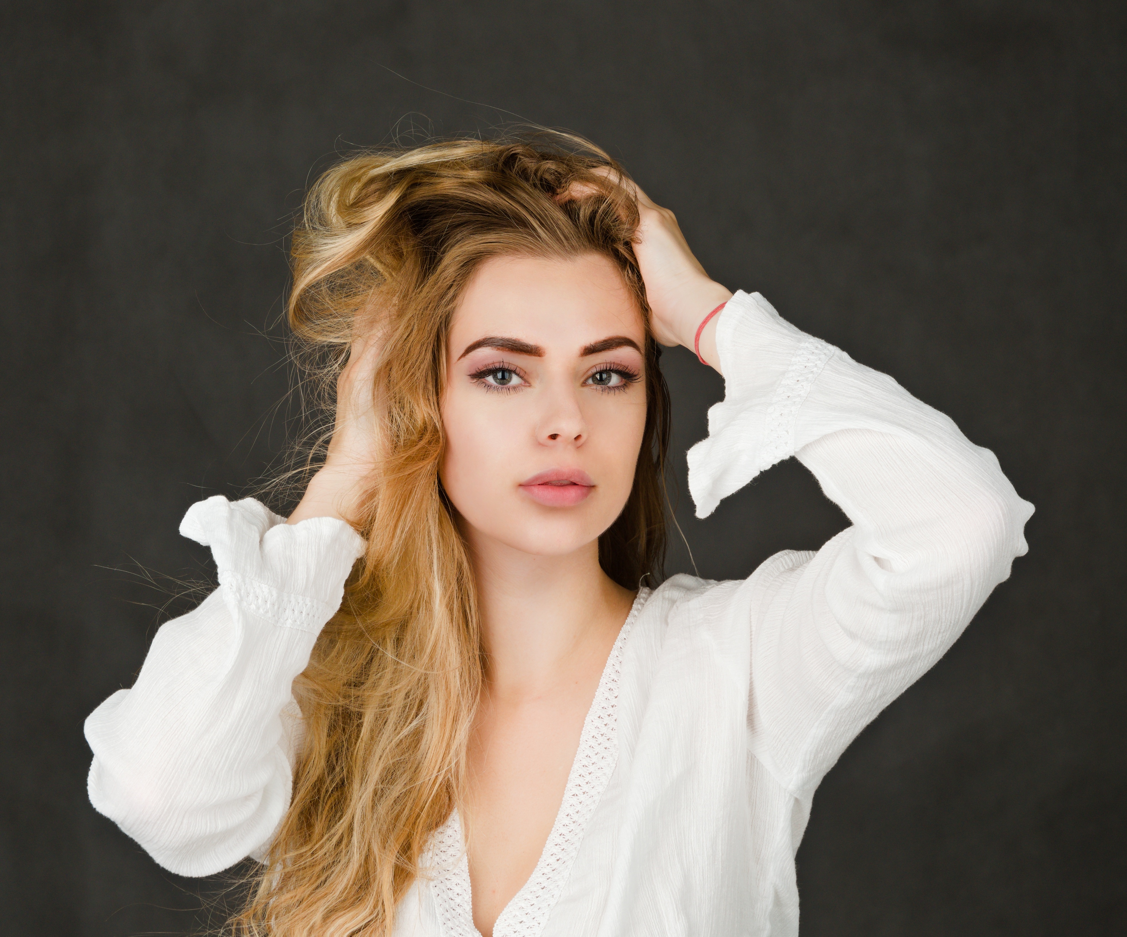 Blonde girl with hands in hair on gray background HD Wallpaper