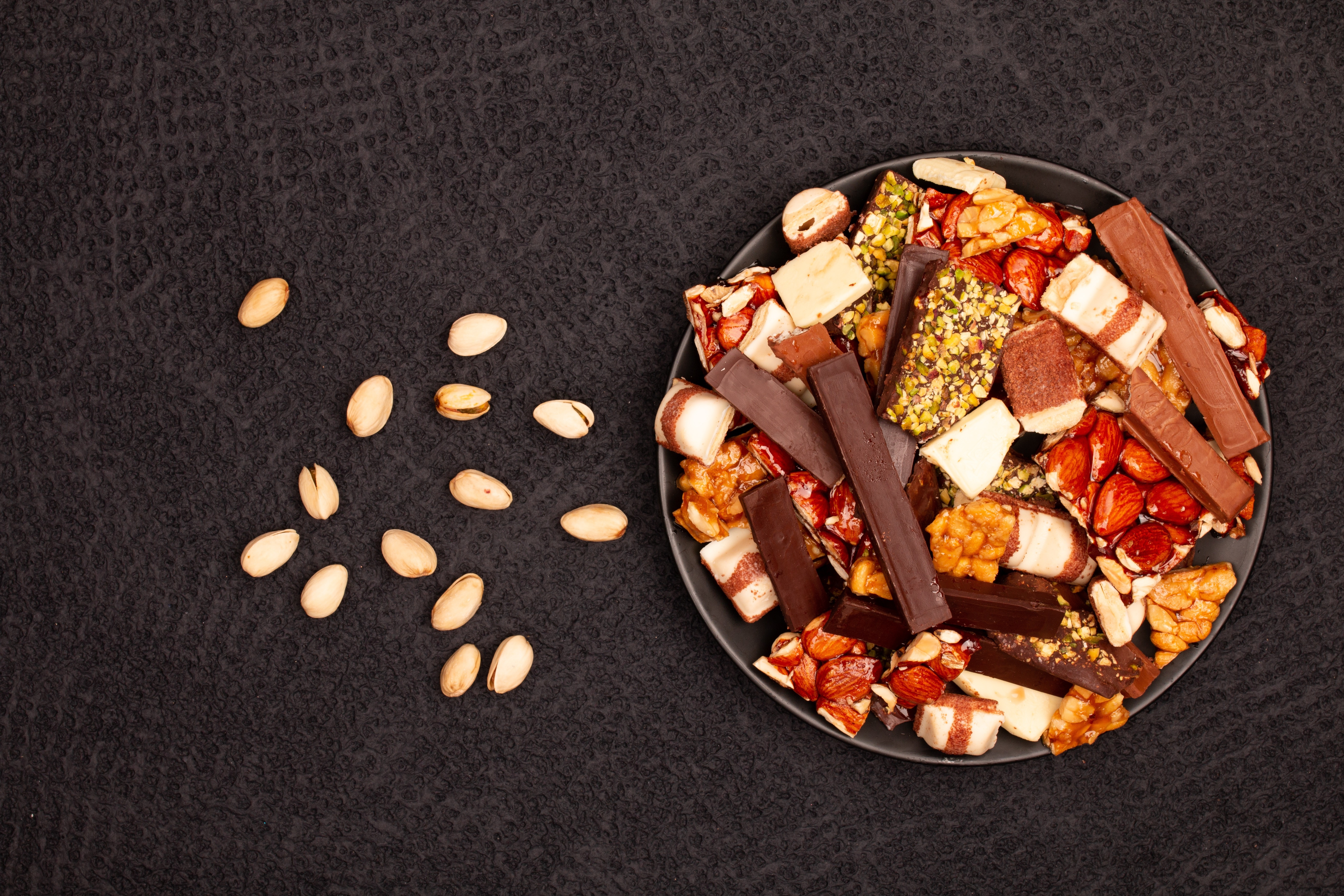 Plate of assorted chocolates and nuts on a gray background HD Wallpaper