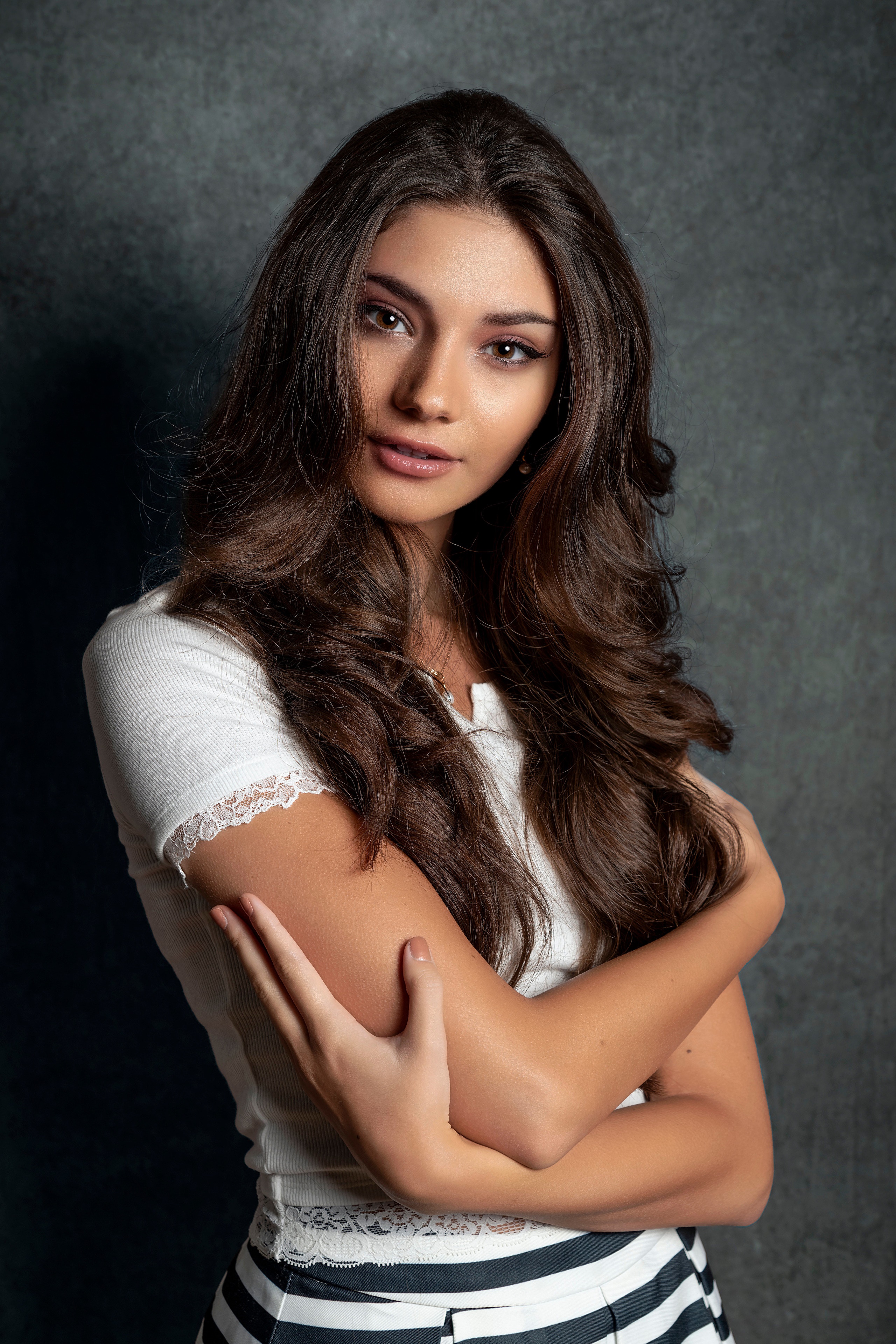 Brunette model with arms crossed, looking to the side HD Phone Wallpaper
