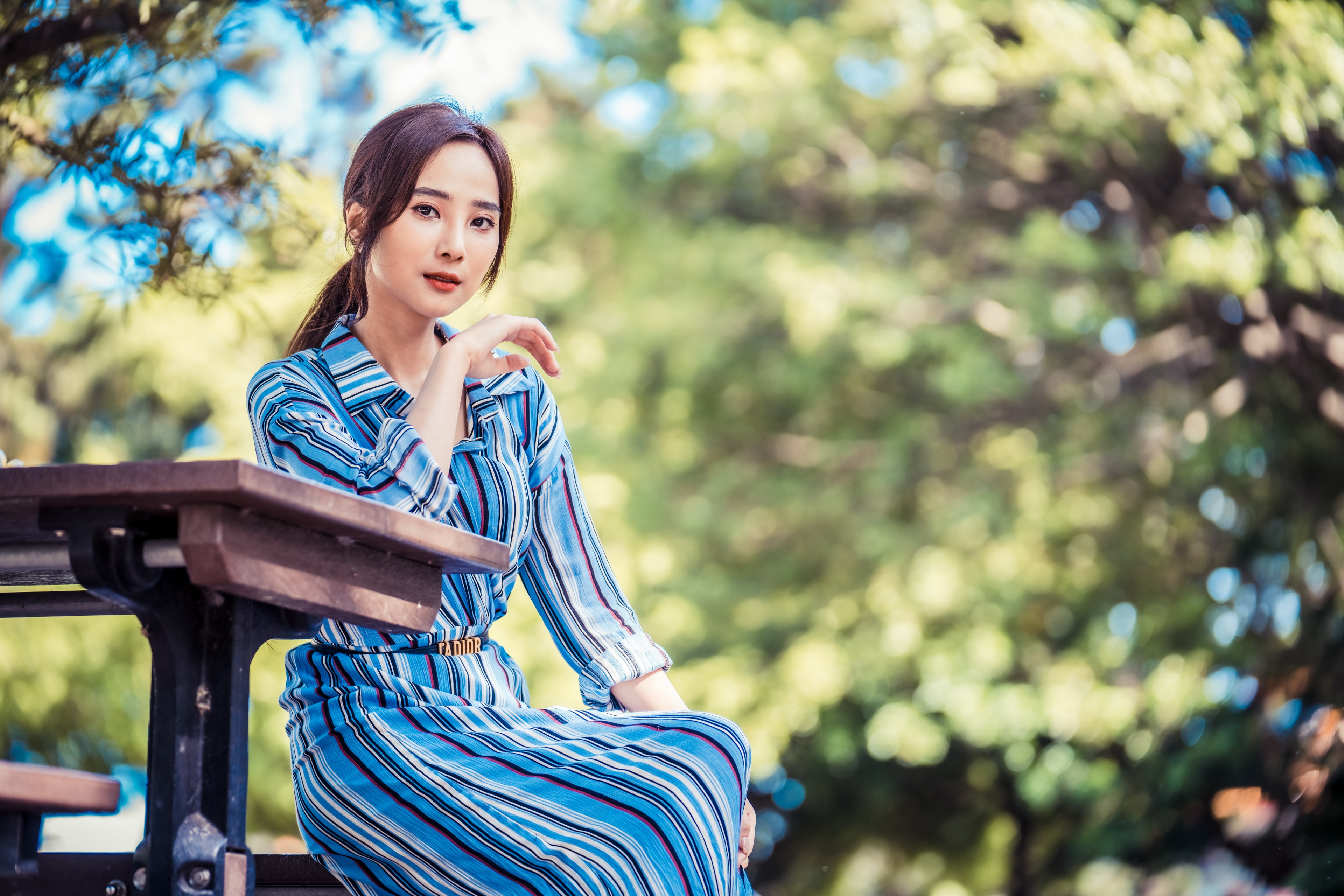 Asian woman sitting at a table outdoors HD Wallpaper
