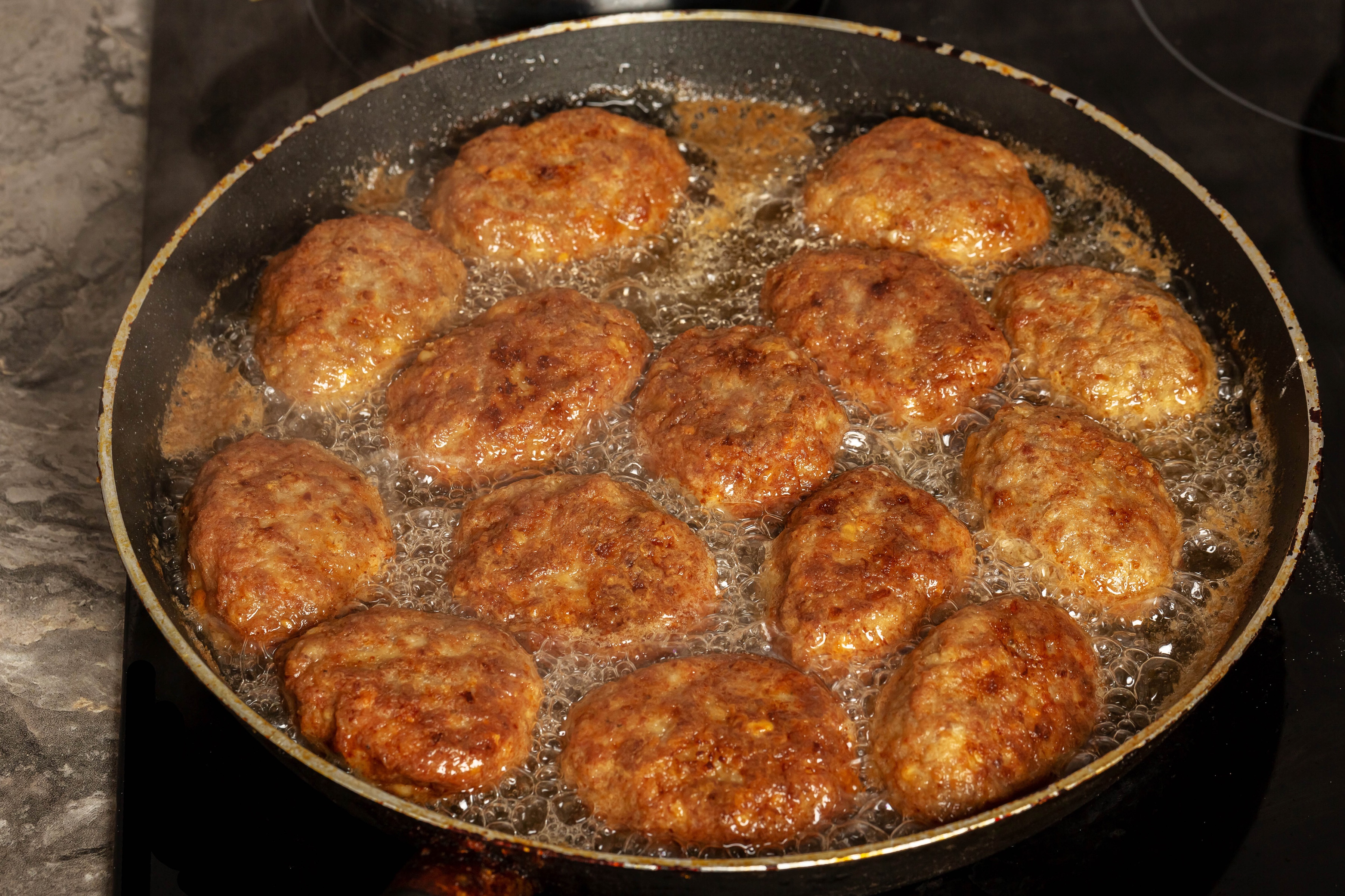 Frikadeller frying in a pan HD Wallpaper