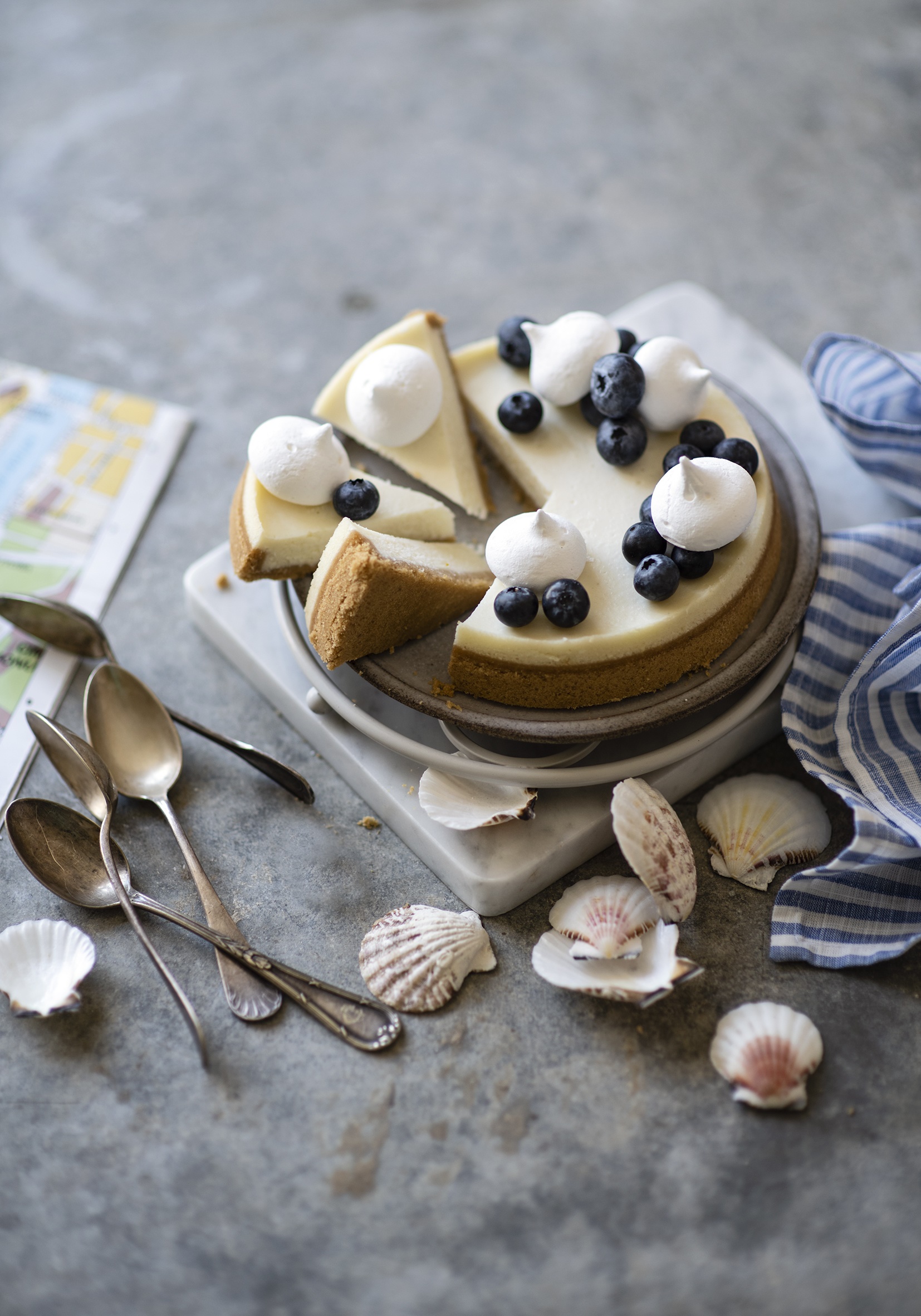 Cheesecake with blueberries and meringue, served with spoons and shells HD Phone Wallpaper