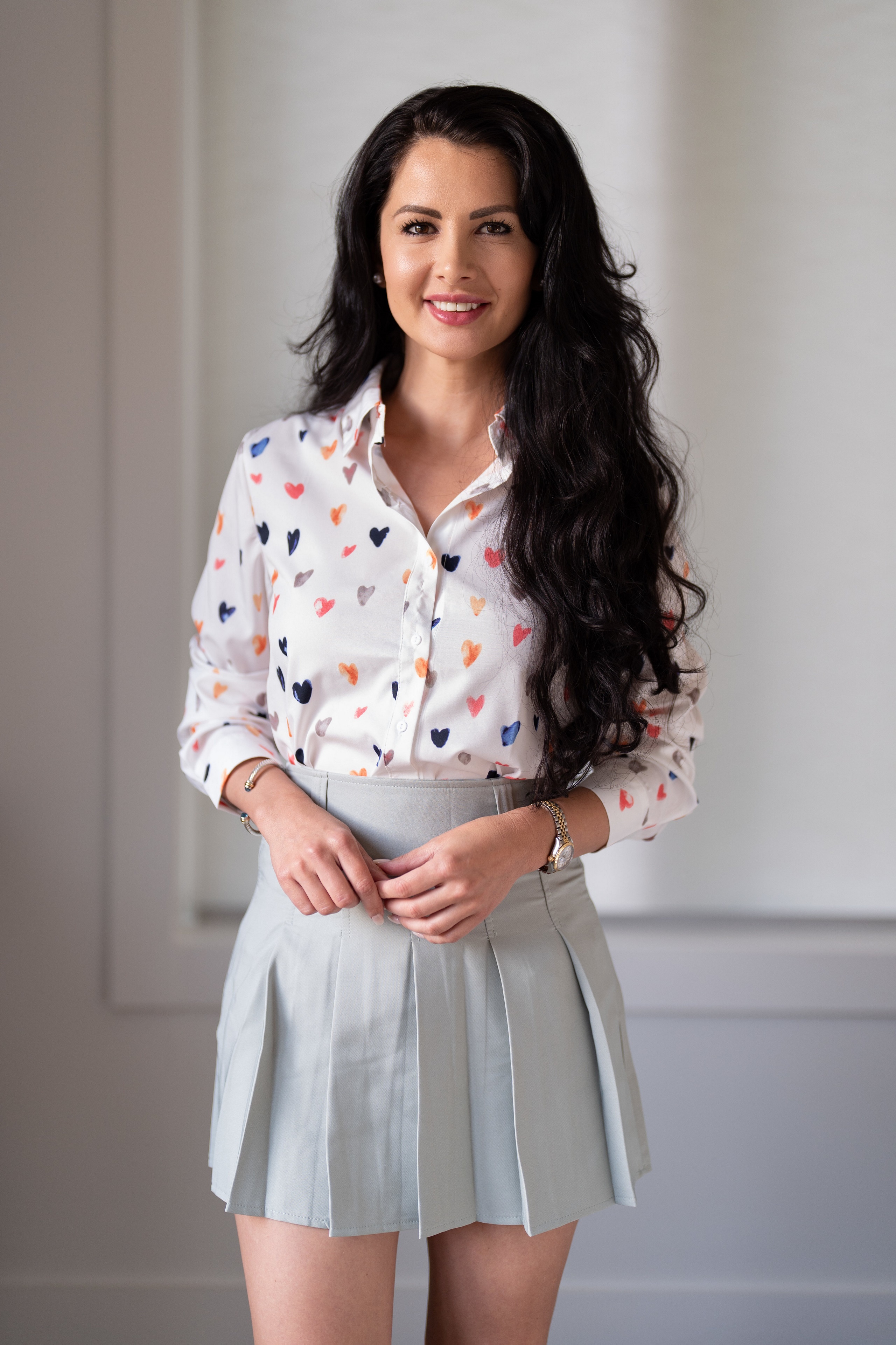 Brunette woman in heart print blouse and pleated skirt HD Phone Wallpaper