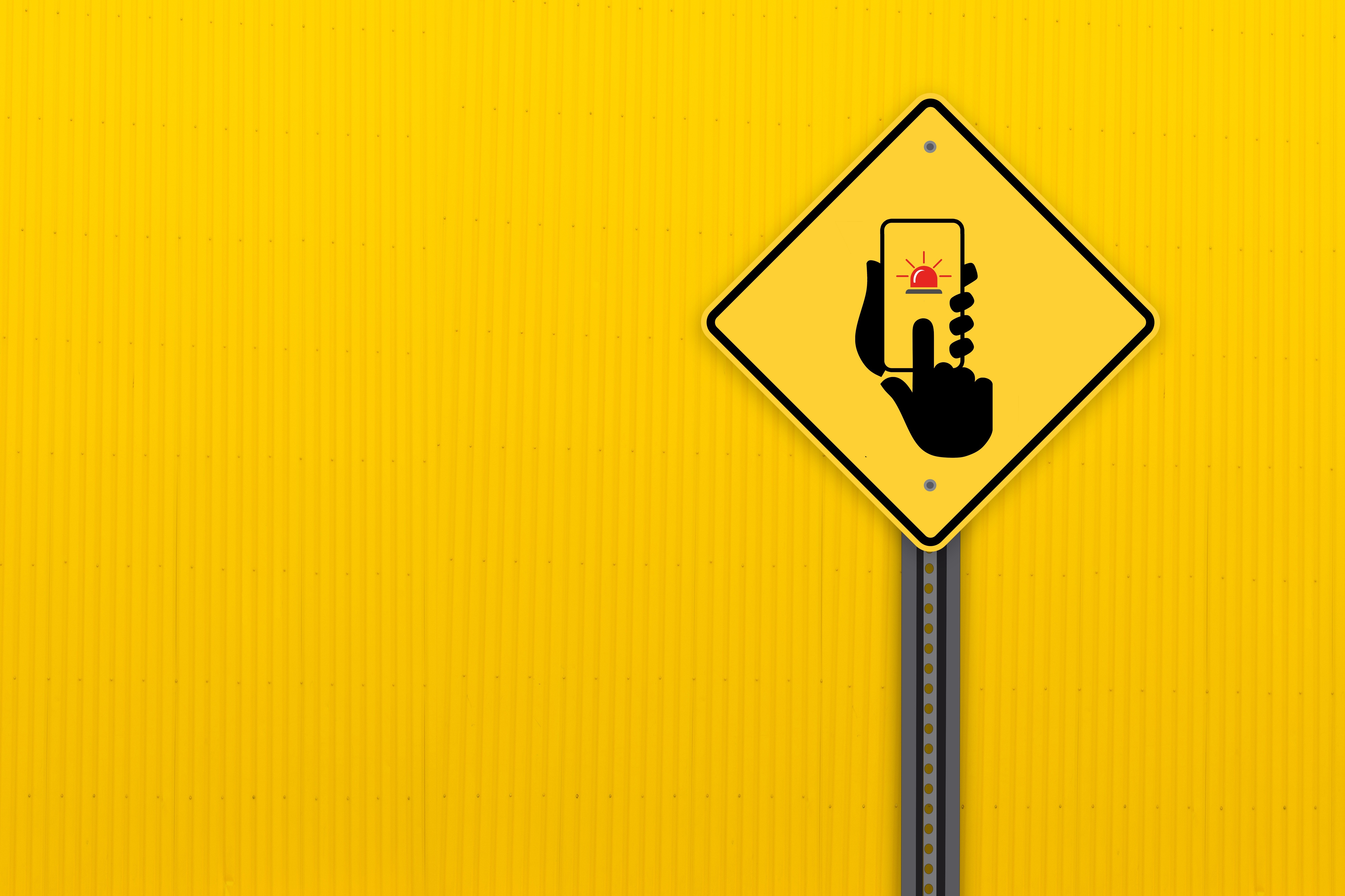 Road sign with hand holding smartphone and alarm icon HD Wallpaper