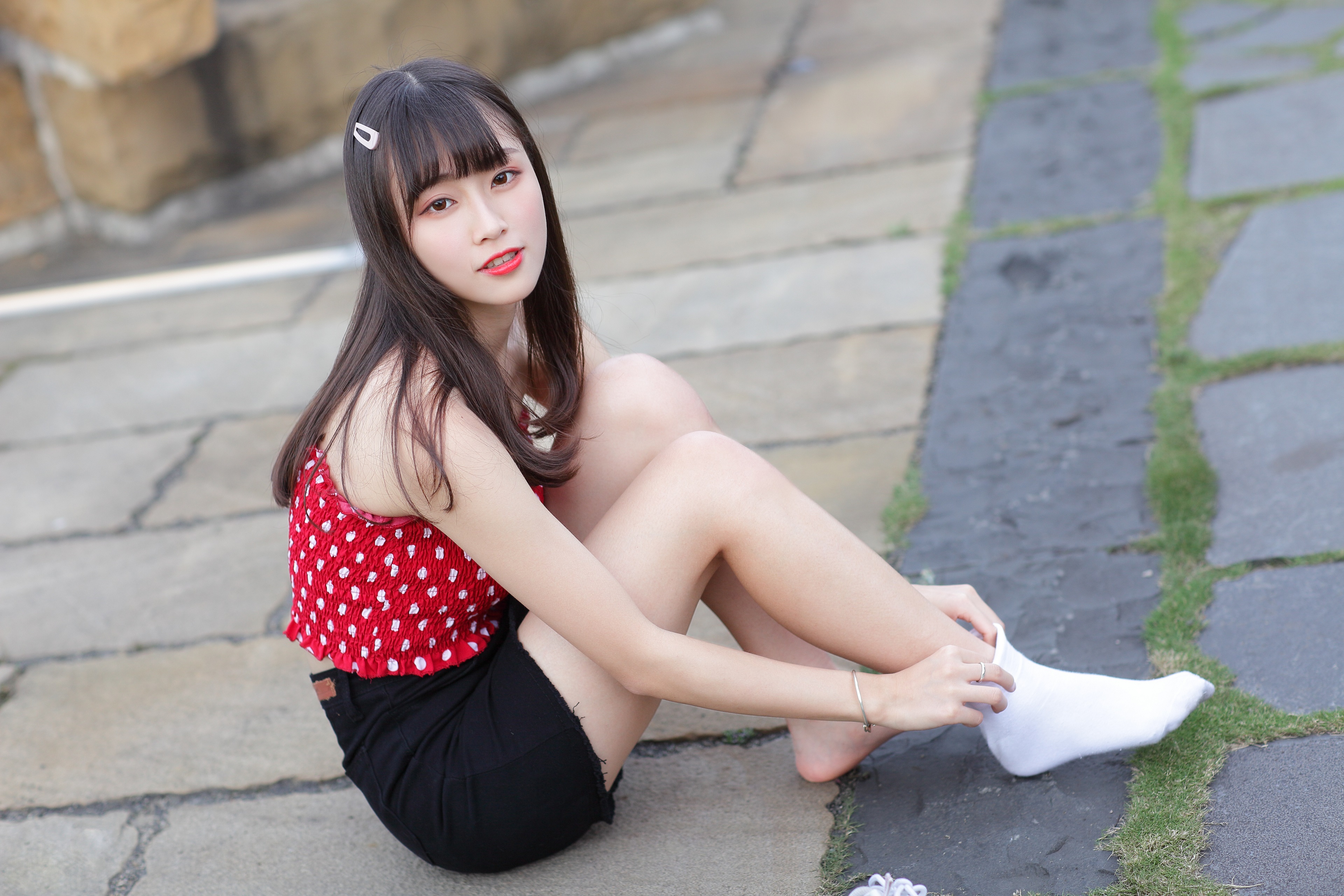 Asian girl sitting on stone path wearing socks HD Wallpaper
