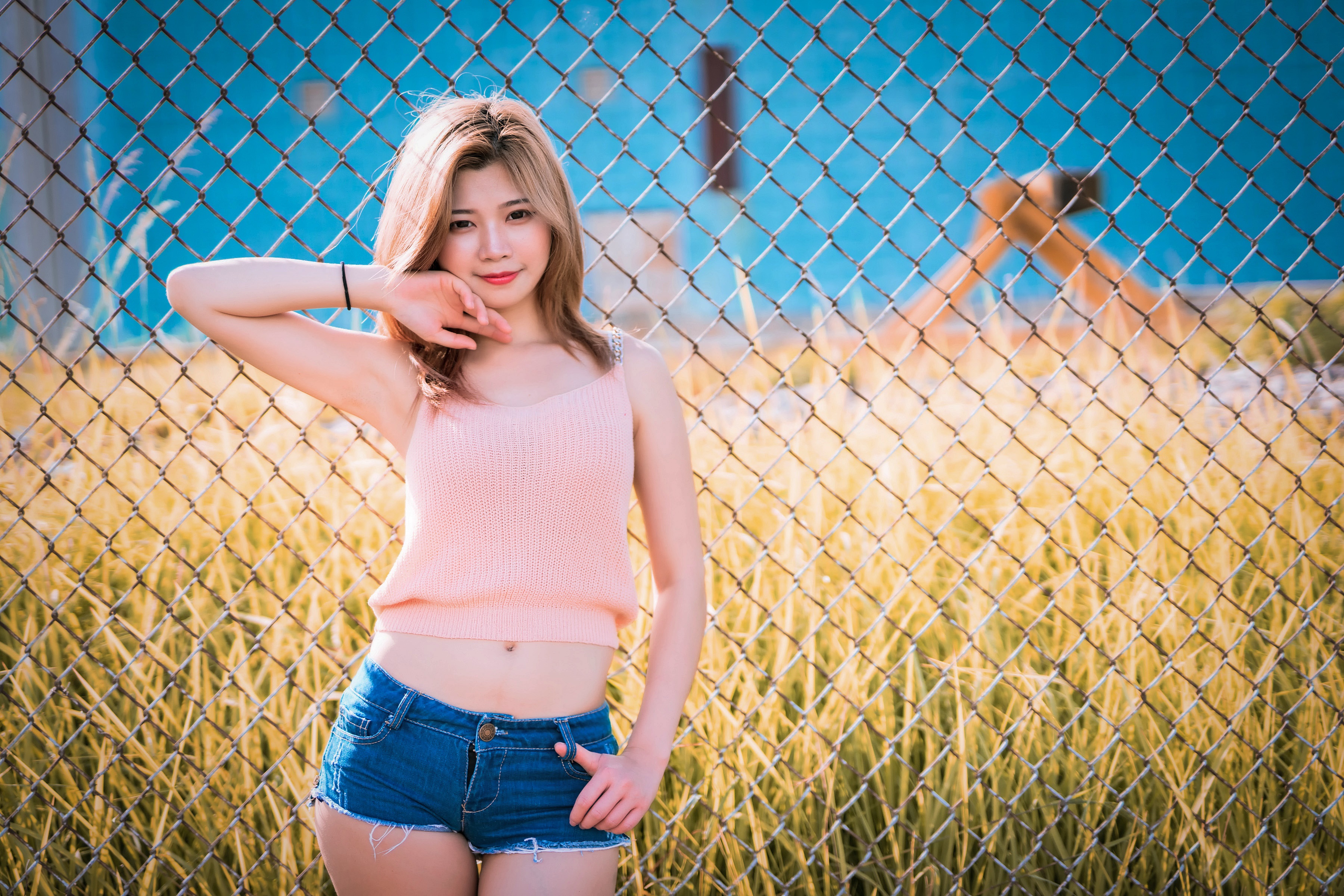 Asian woman in pink singlet and denim shorts posing HD Wallpaper
