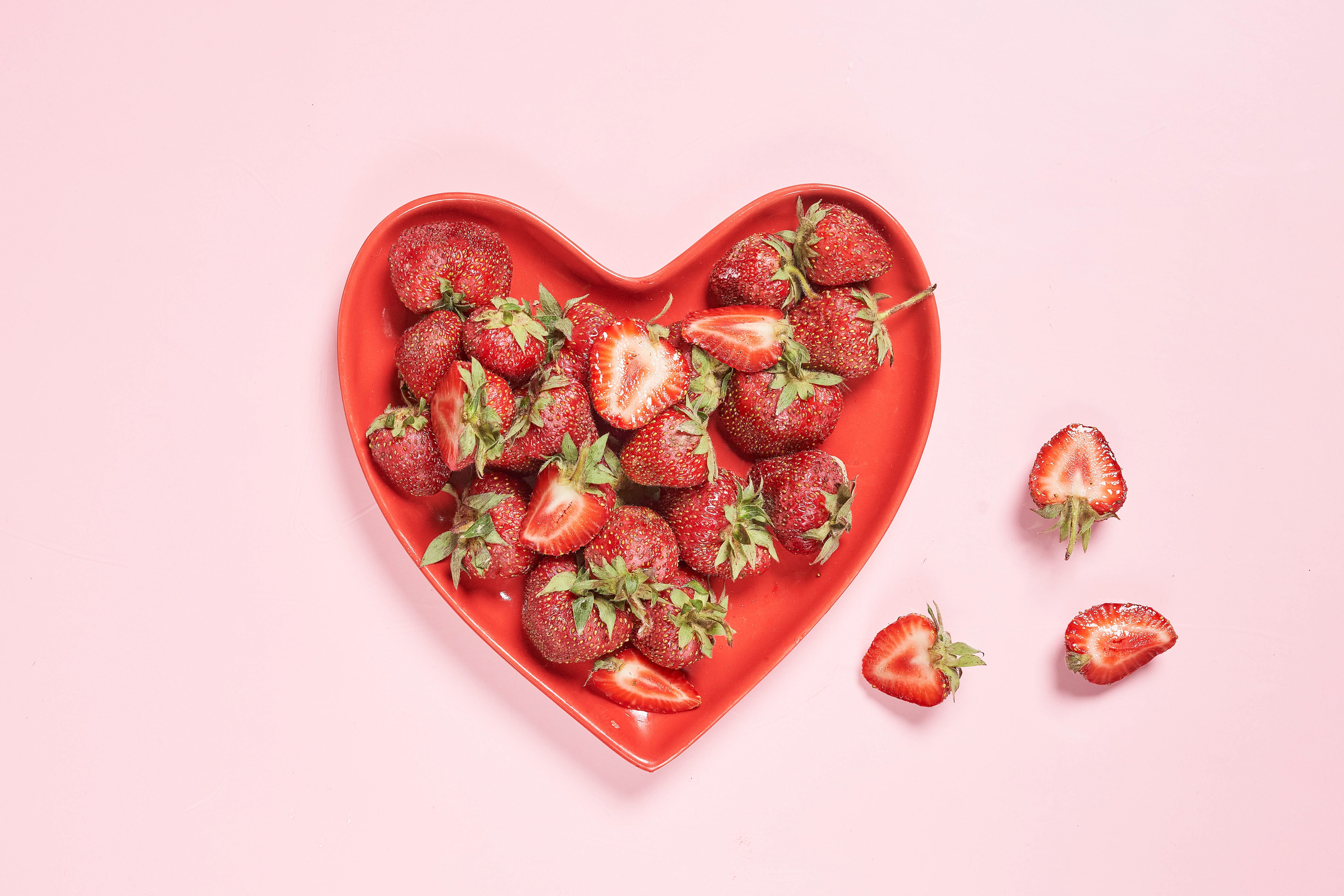 Strawberries in a heart-shaped bowl on pink background HD Wallpaper