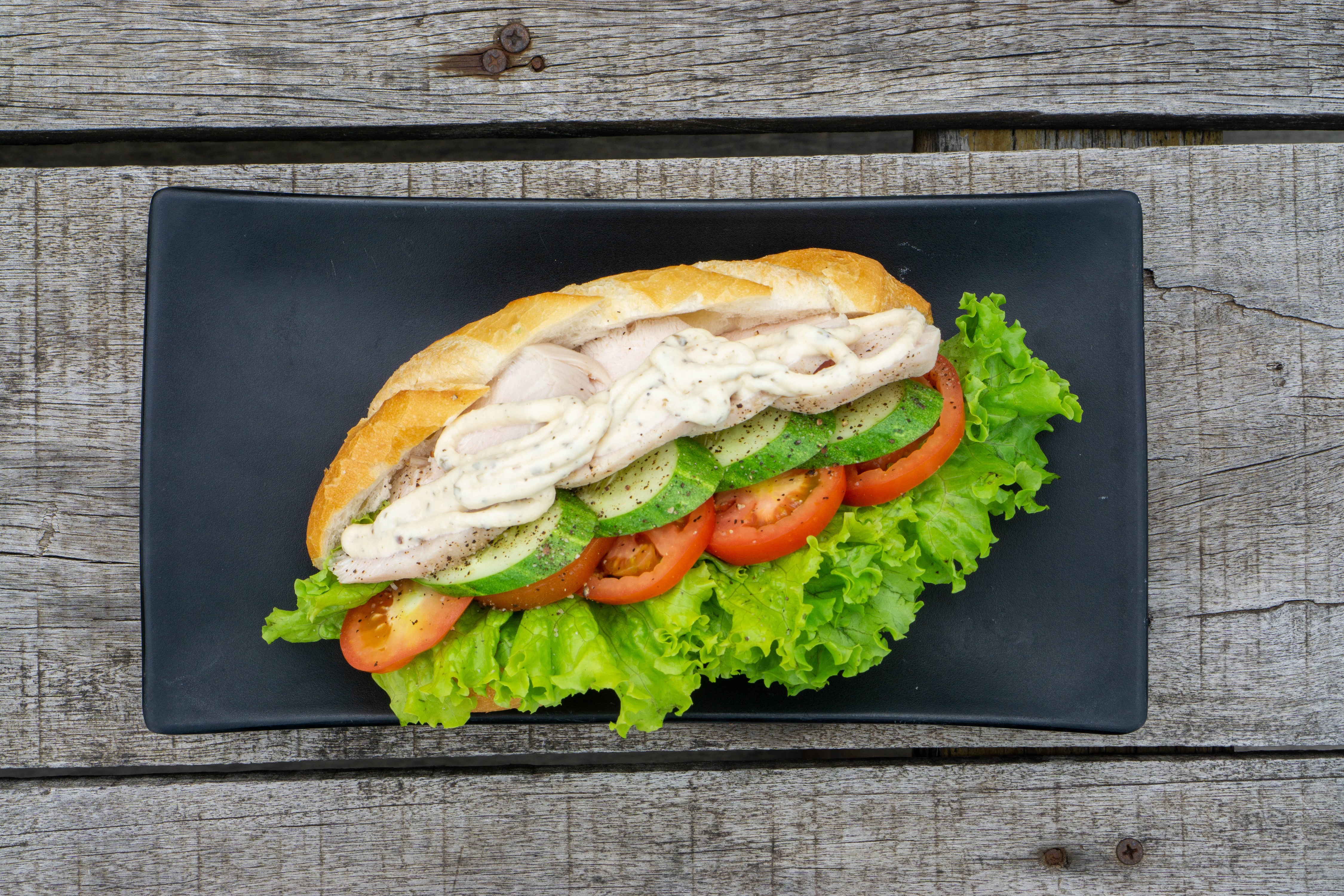 Sandwich with chicken, vegetables, and sauce on a plate HD Wallpaper