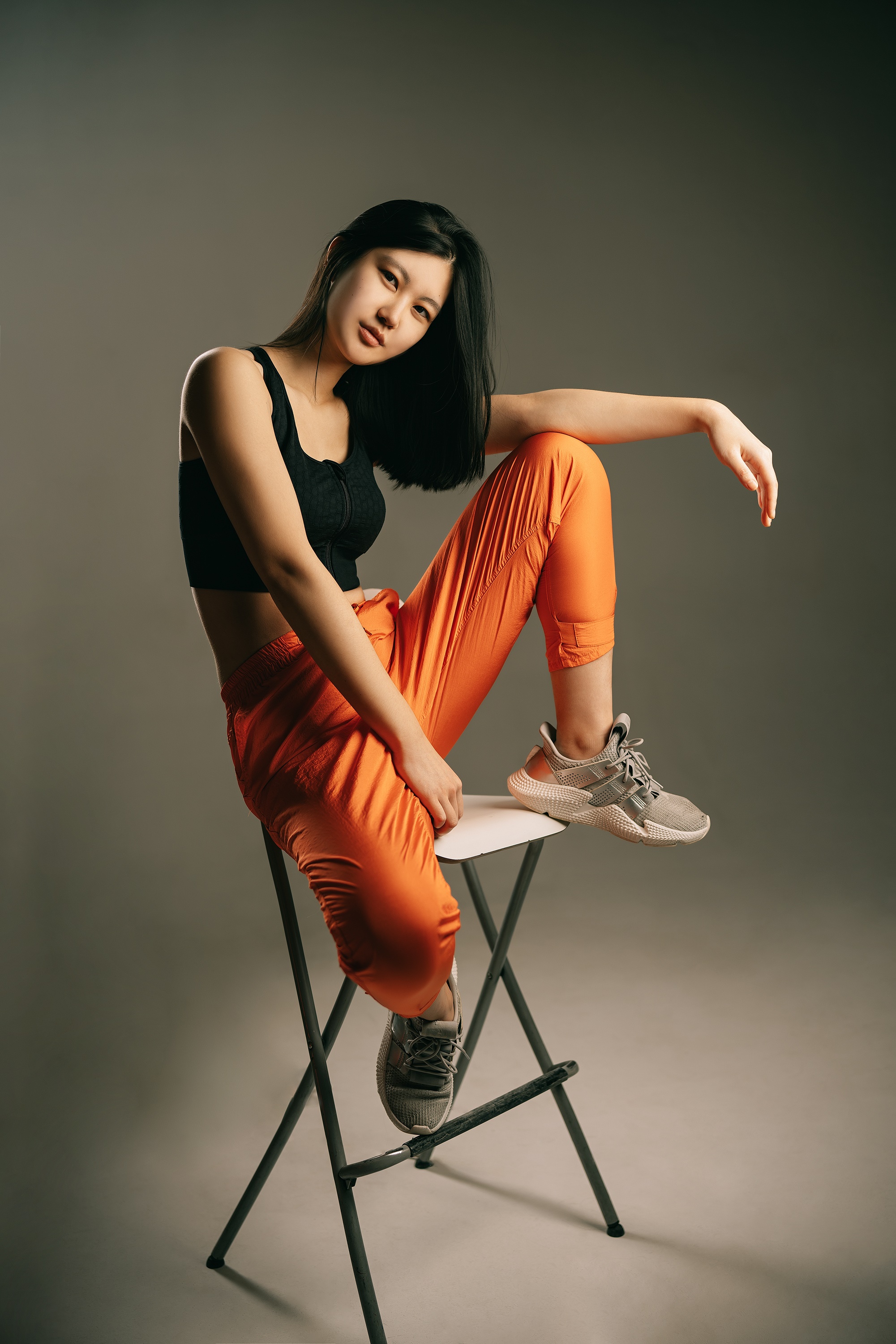 Woman in orange pants sitting on a stool HD Phone Wallpaper
