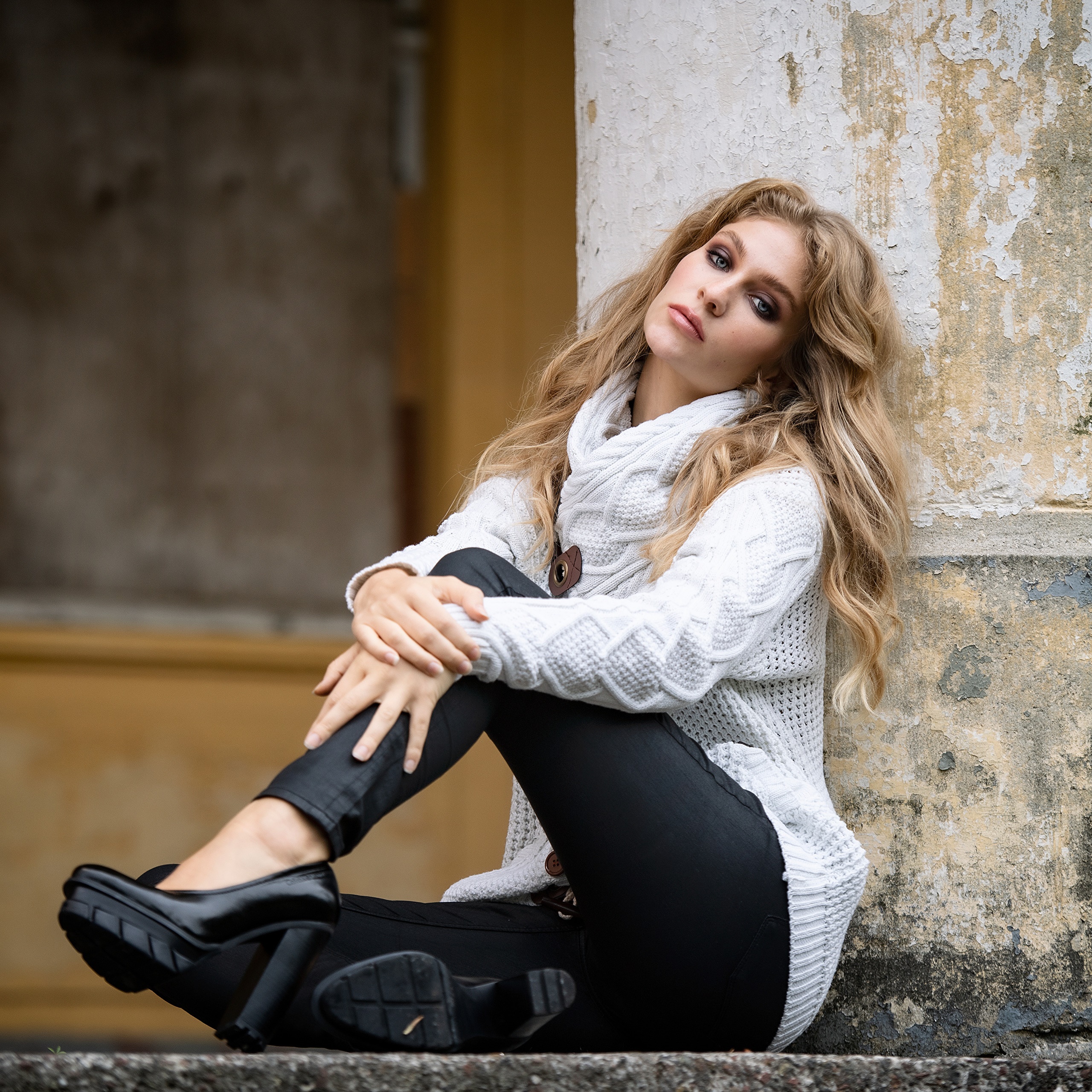 Woman in white sweater sitting by a column HD Wallpaper