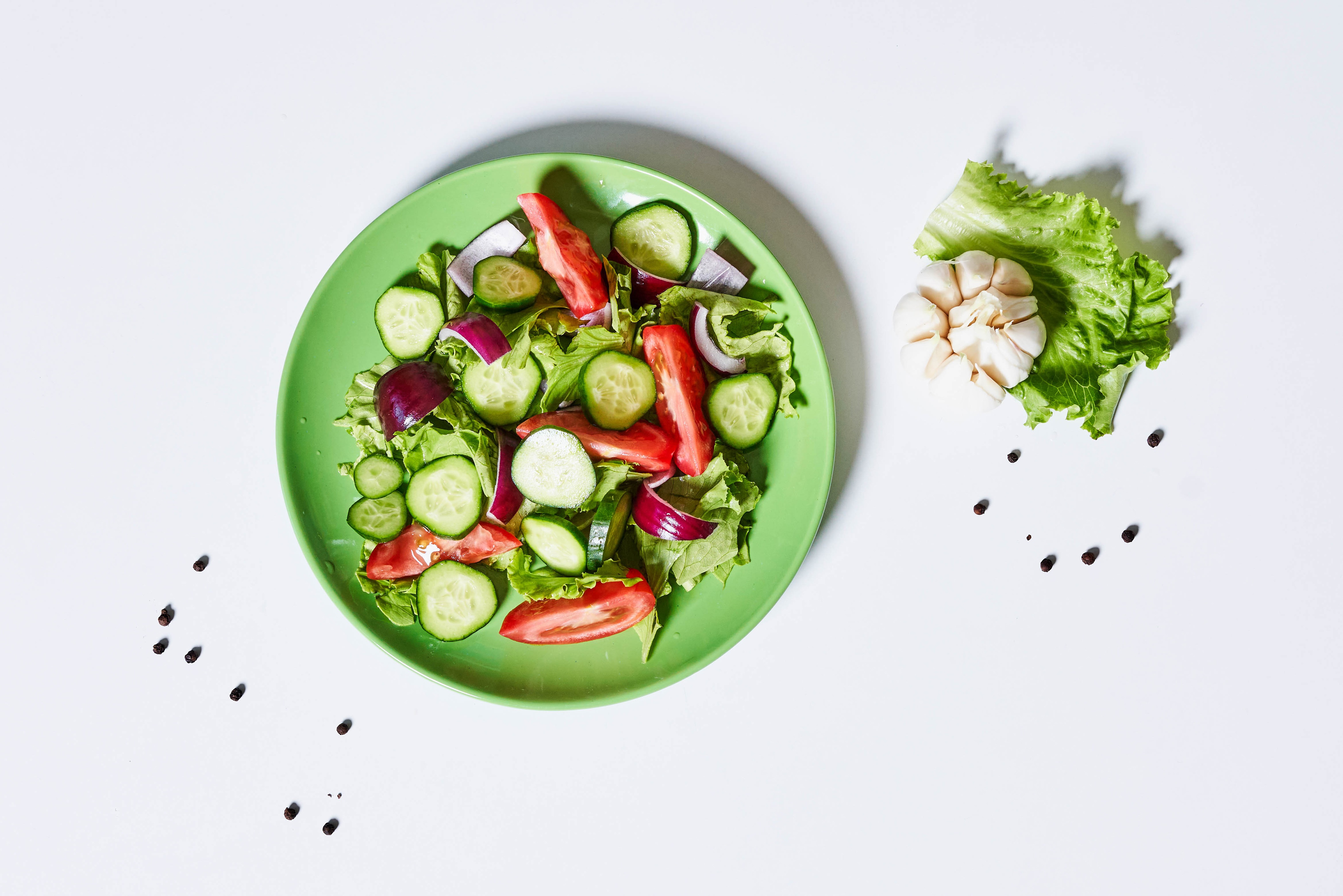 Salad with cucumber, tomato, onion, garlic, and black pepper on white background HD Wallpaper