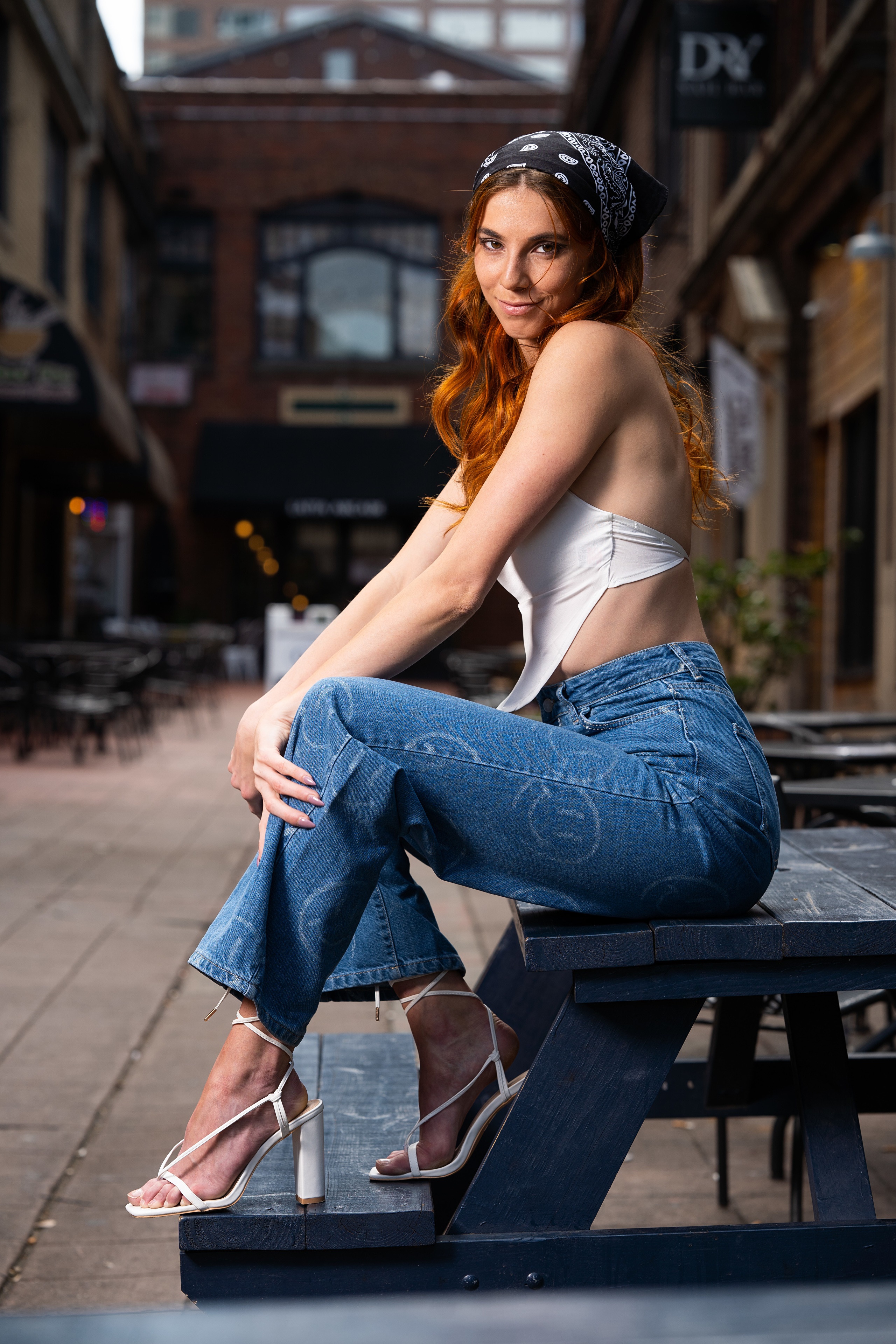 Redhead woman in jeans and white top sitting outdoors HD Phone Wallpaper