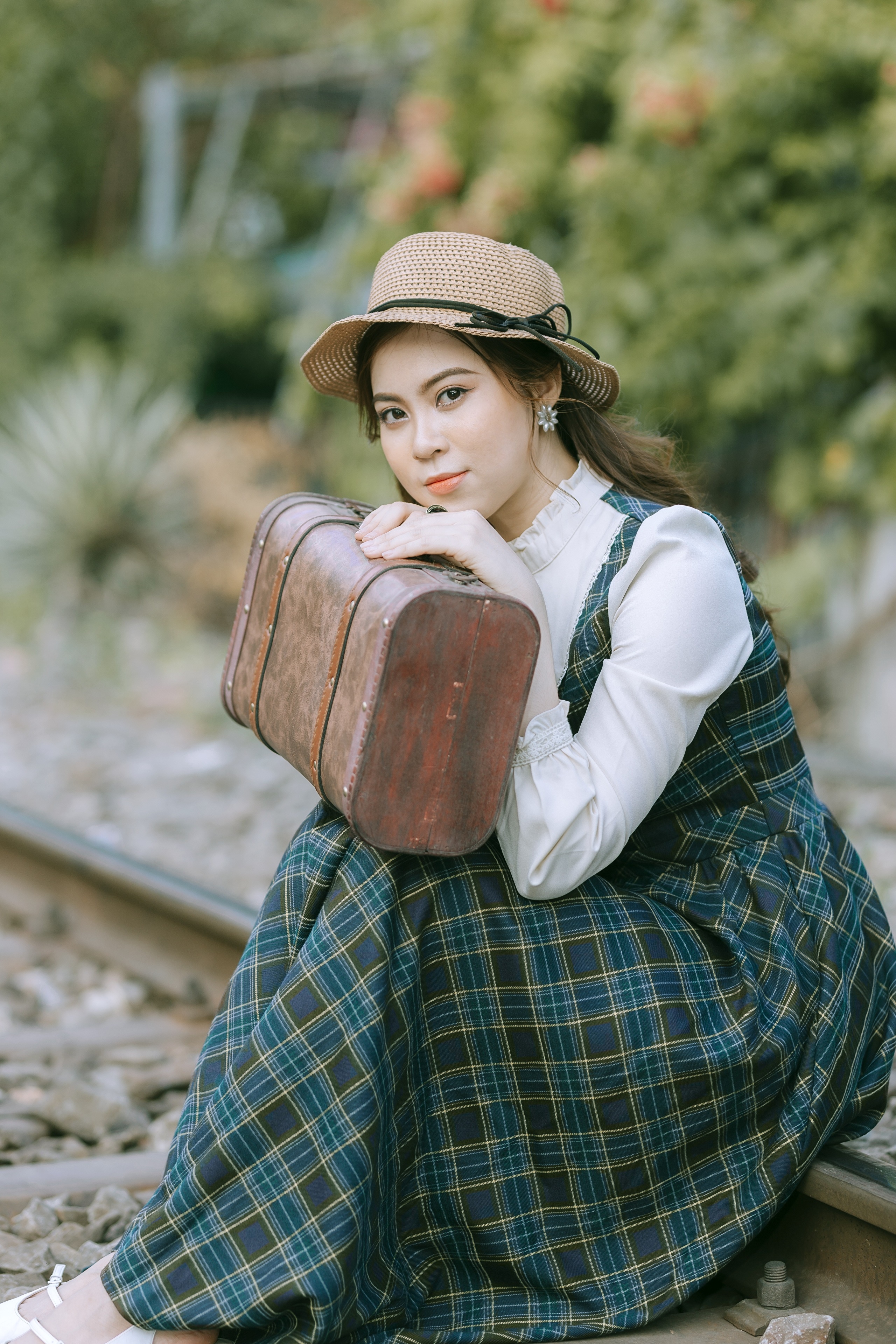 Woman in vintage dress and hat with suitcase on train tracks HD Phone Wallpaper