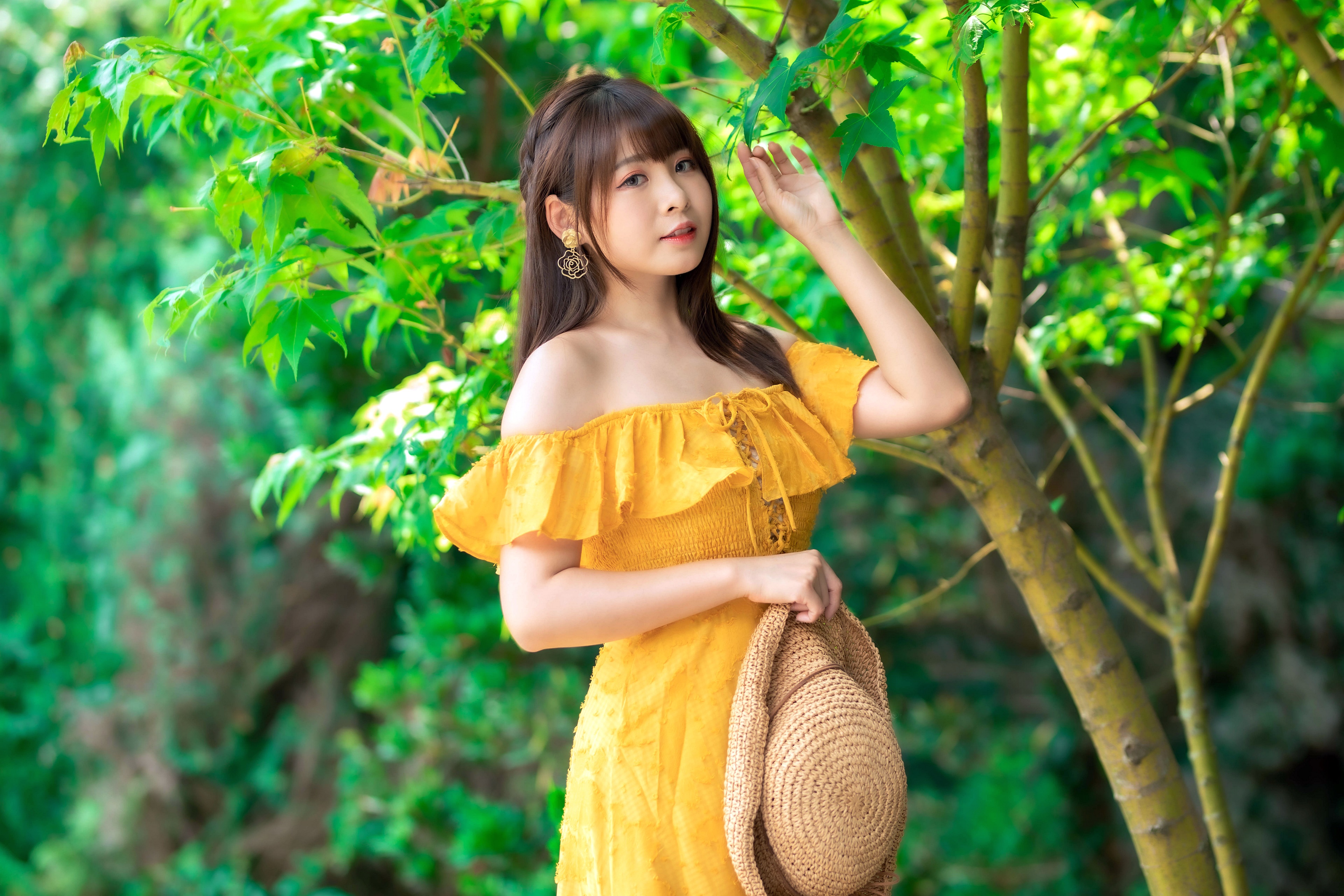 Asian woman in yellow dress holding a hat HD Wallpaper