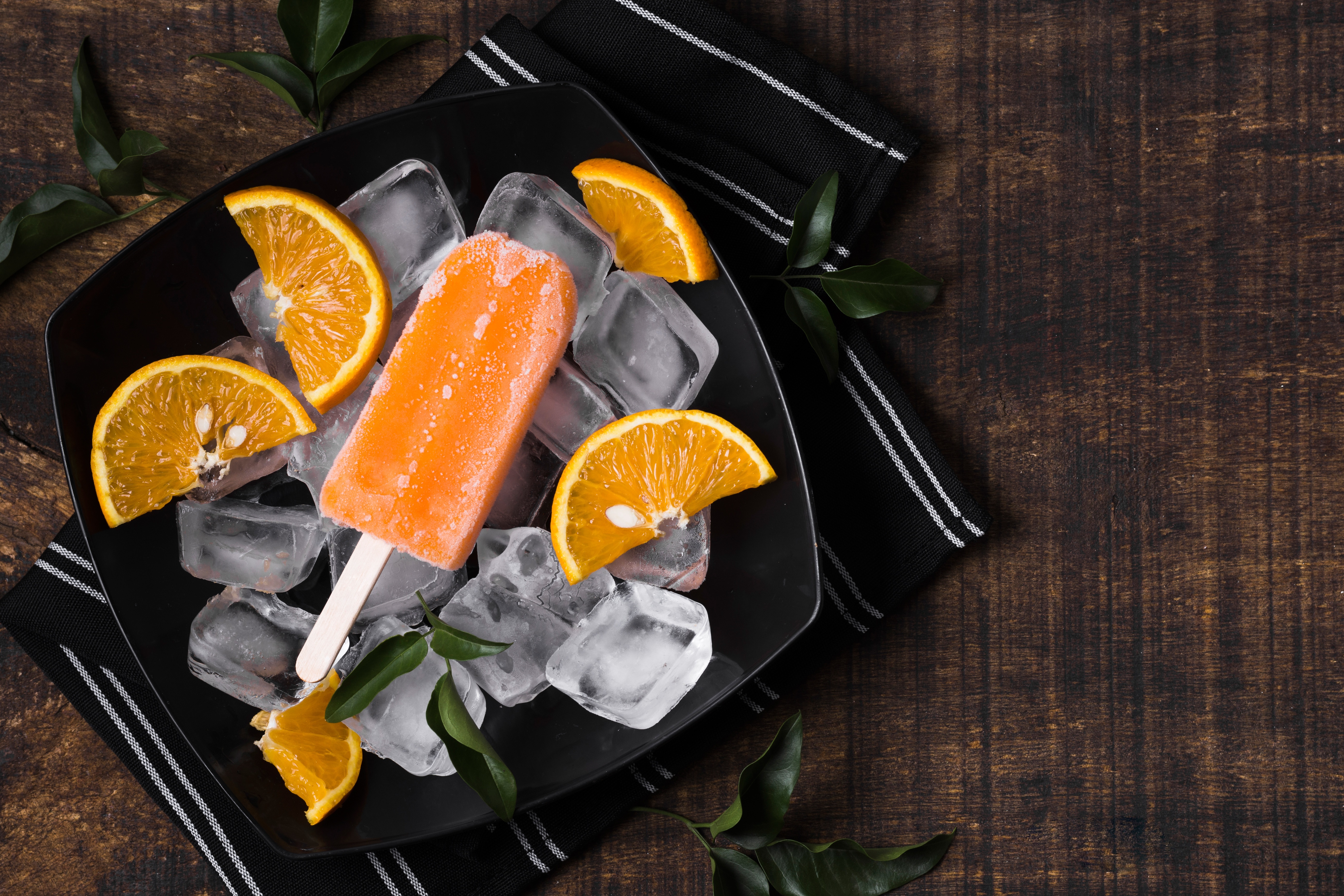 Orange popsicle with ice and orange slices on a plate HD Wallpaper