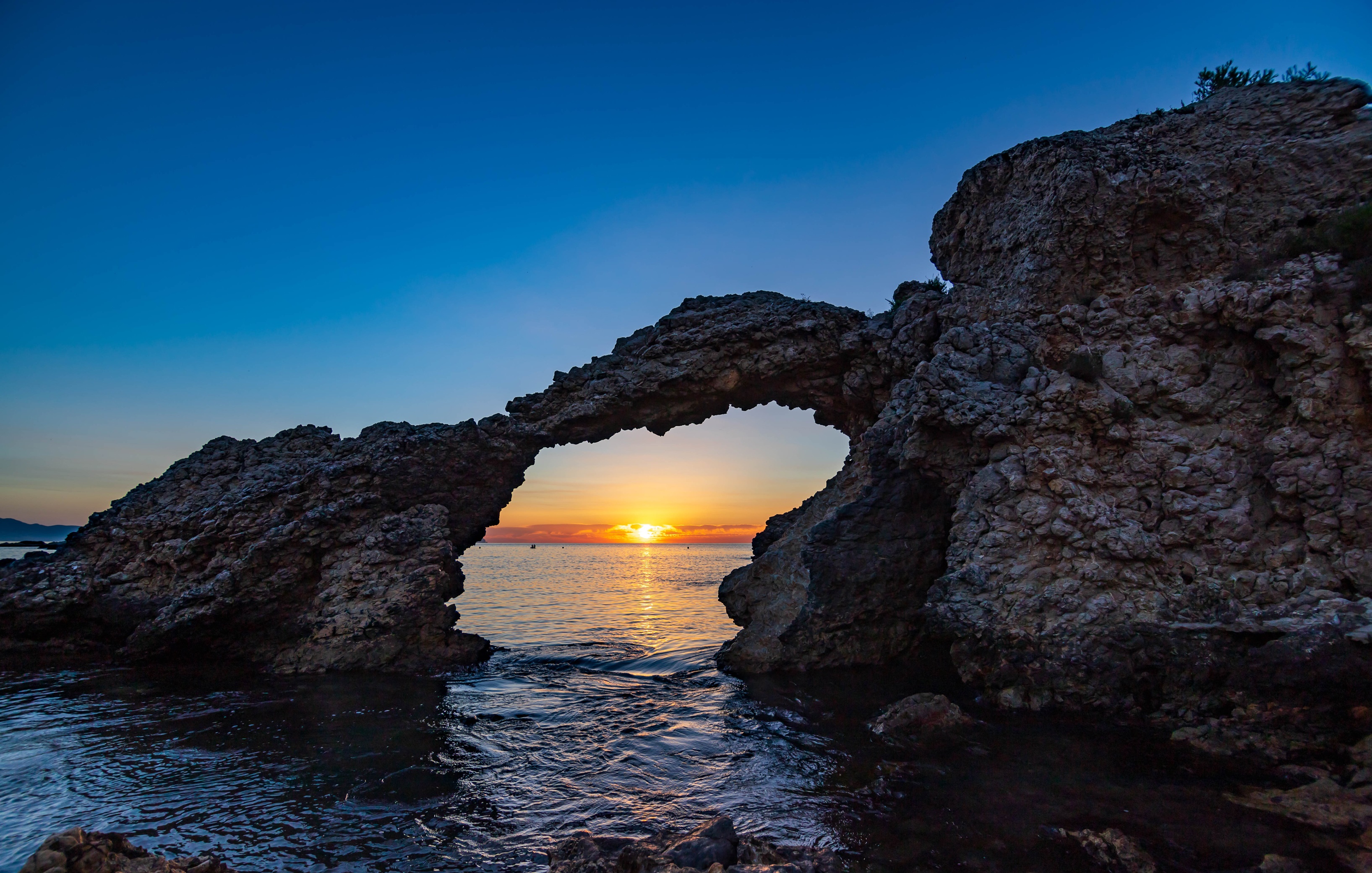 Sunrise through a rock arch in Girona, Spain HD Wallpaper