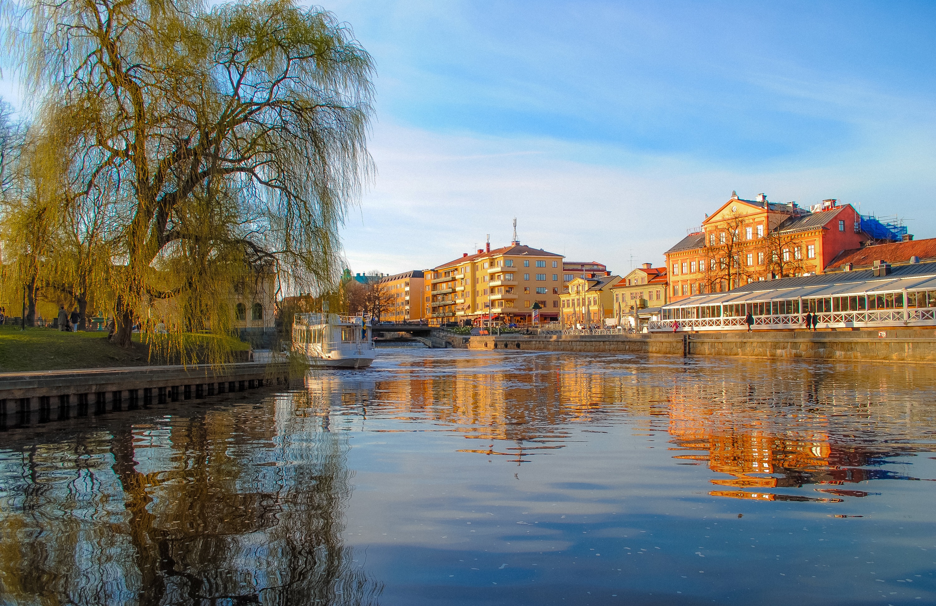 Riverboat on a river in Uppsala, Sweden with buildings and trees HD Wallpaper
