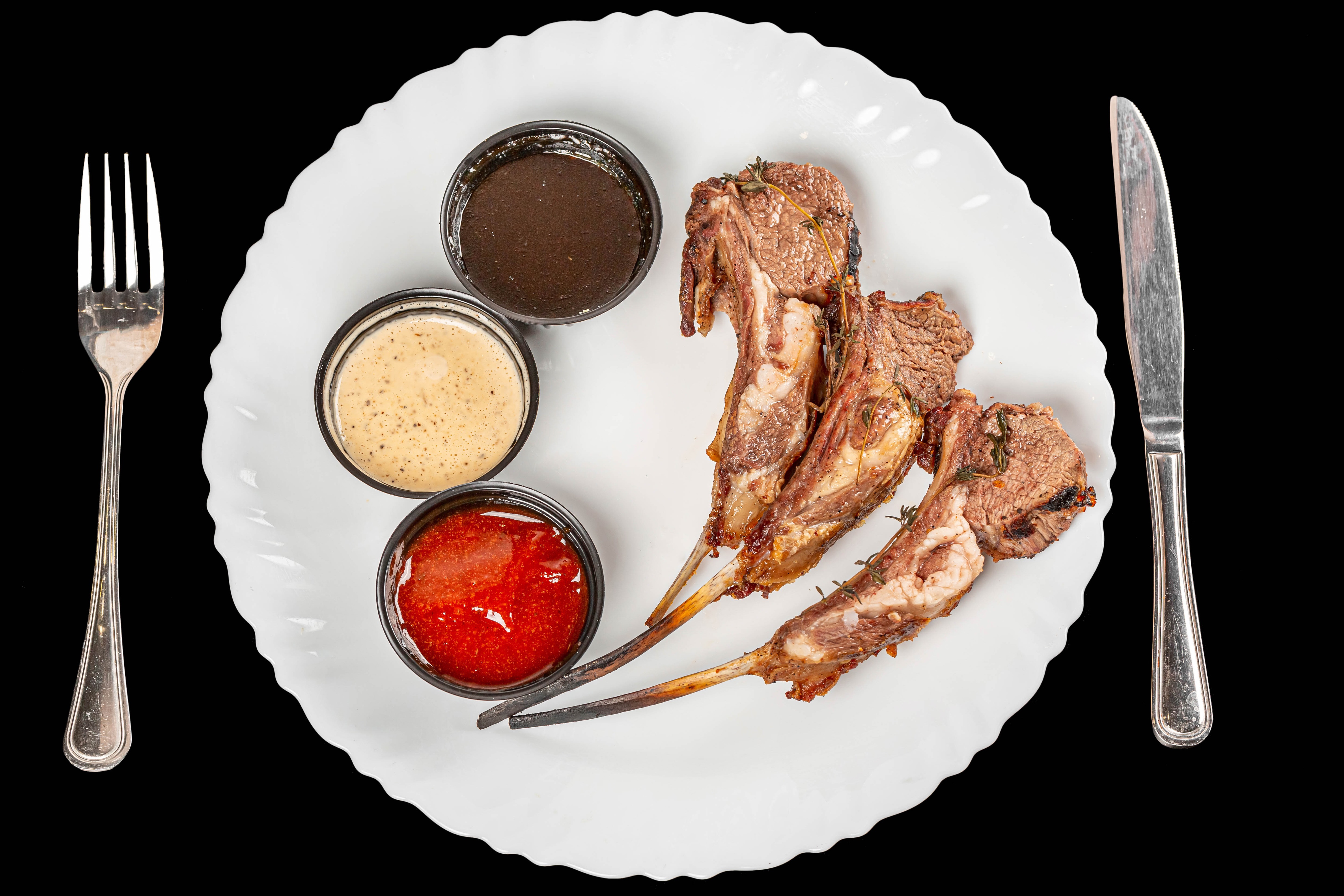 Rack of lamb with three dipping sauces on a plate HD Wallpaper