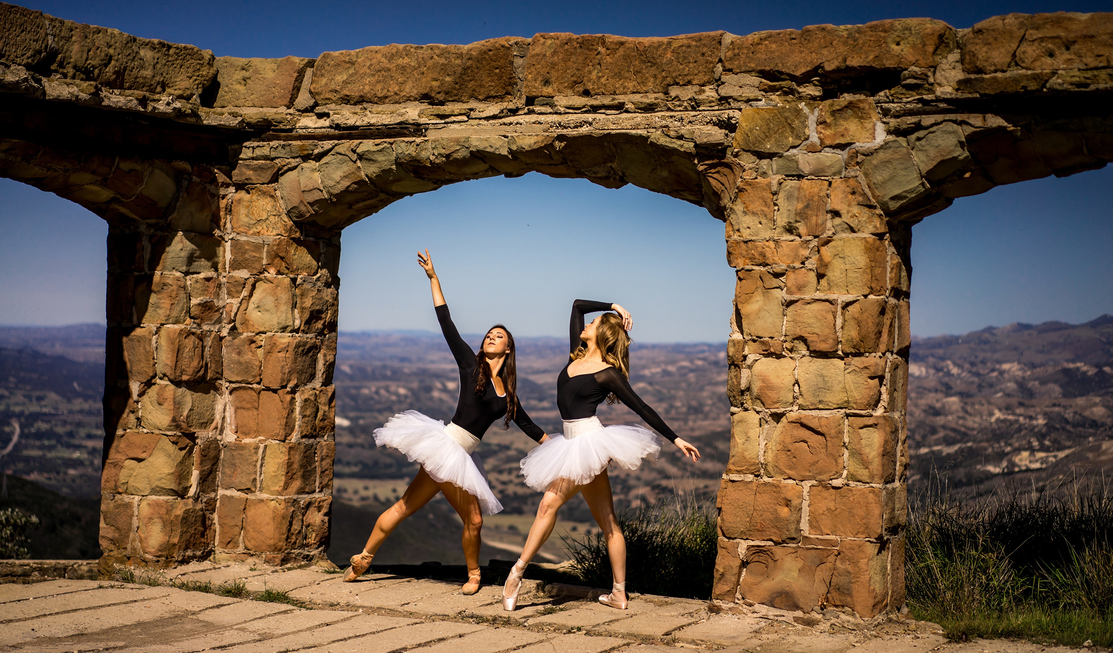 Two ballerinas dancing through a stone archway HD Wallpaper