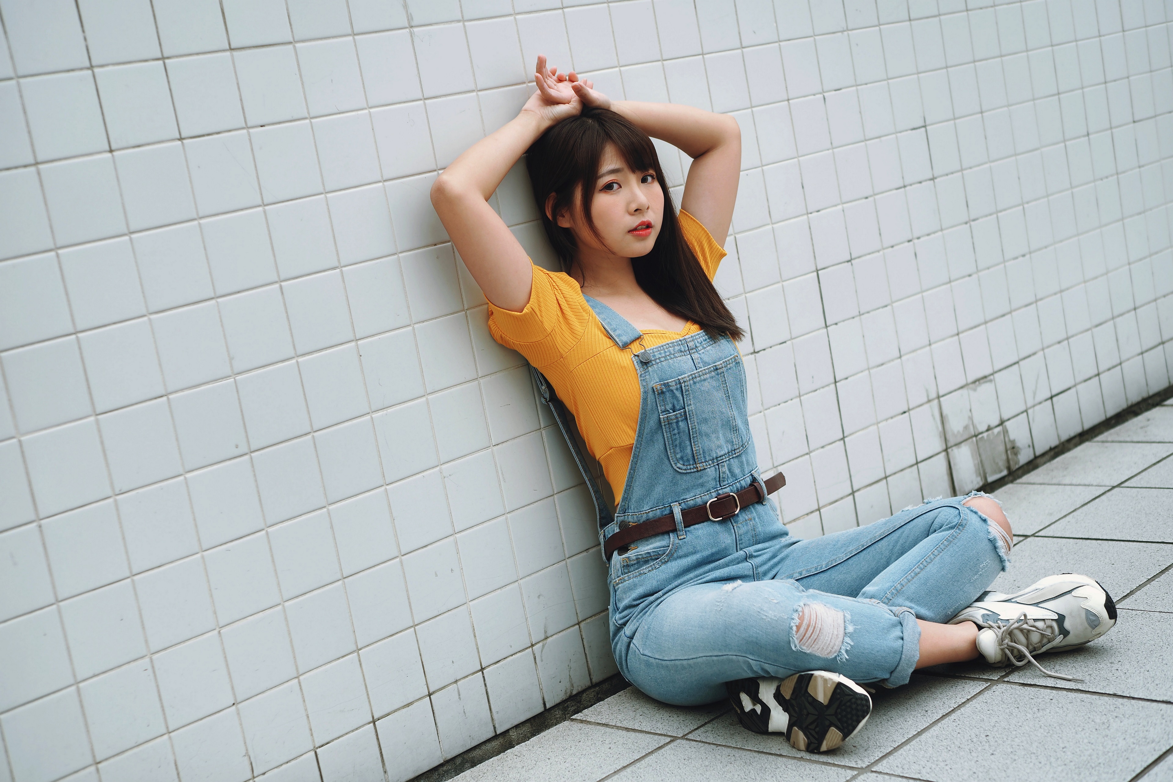Asian girl sitting by a tiled wall HD Wallpaper