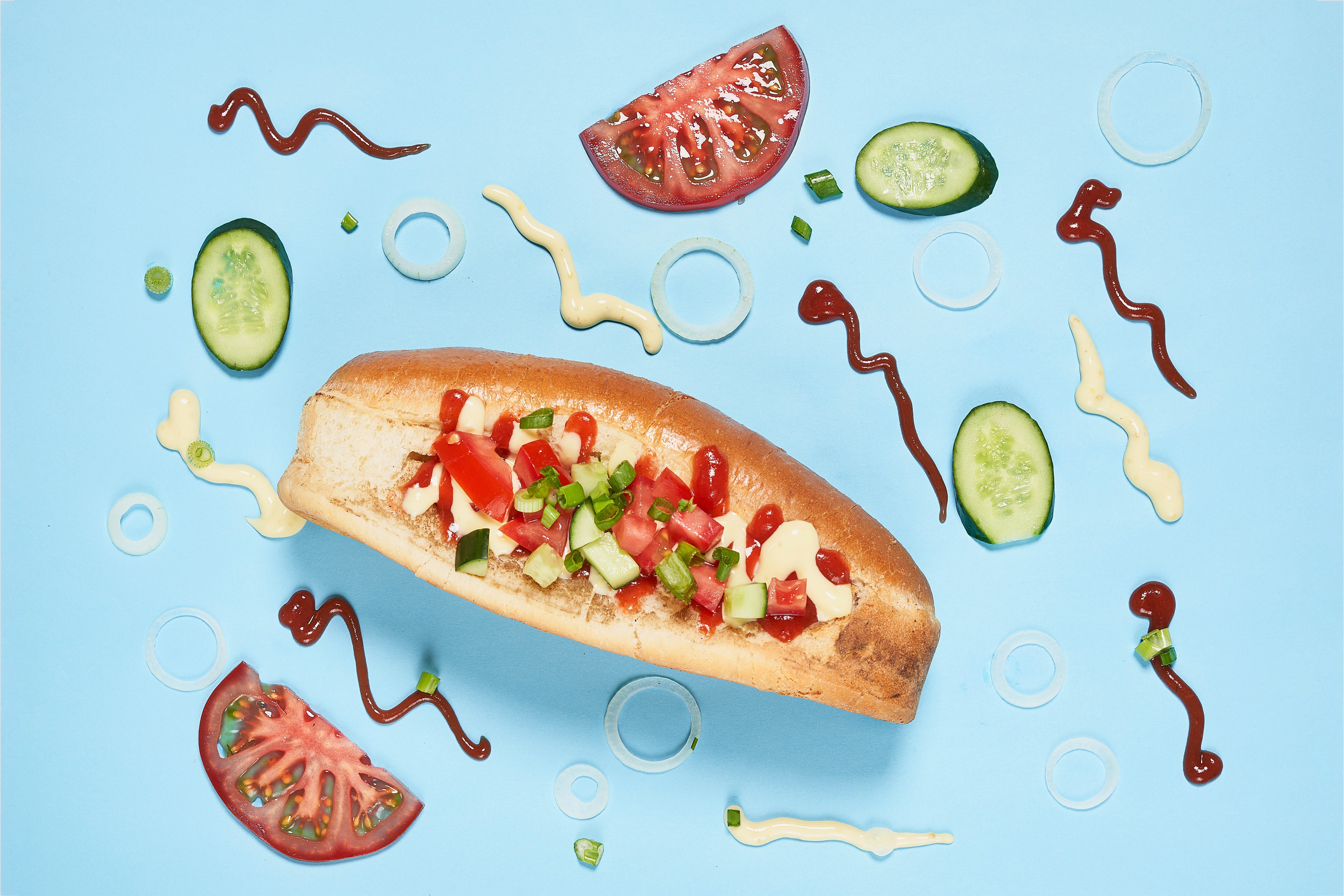 Hot dog with toppings and ingredients on blue background HD Wallpaper