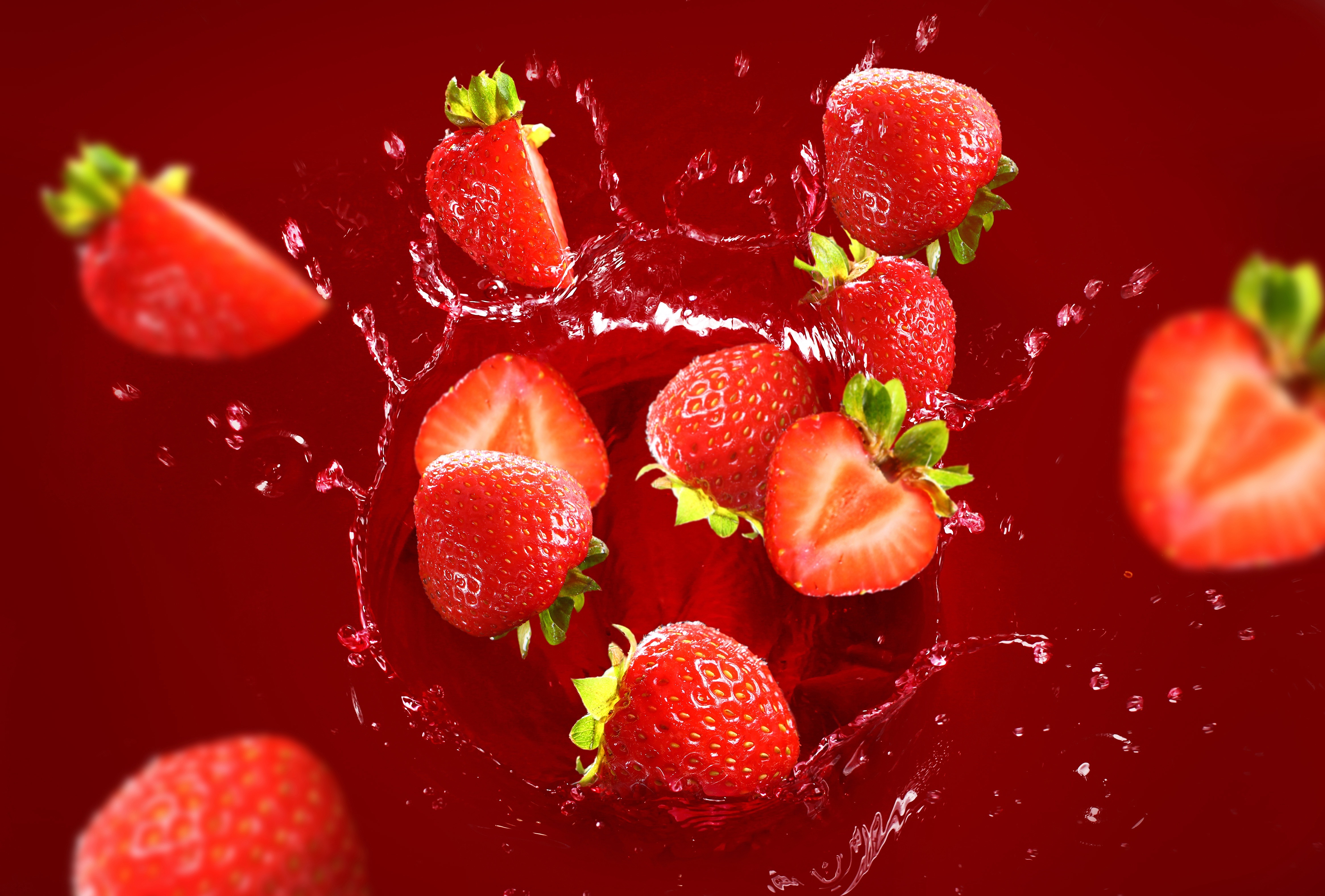 Strawberries splashing in red liquid HD Wallpaper