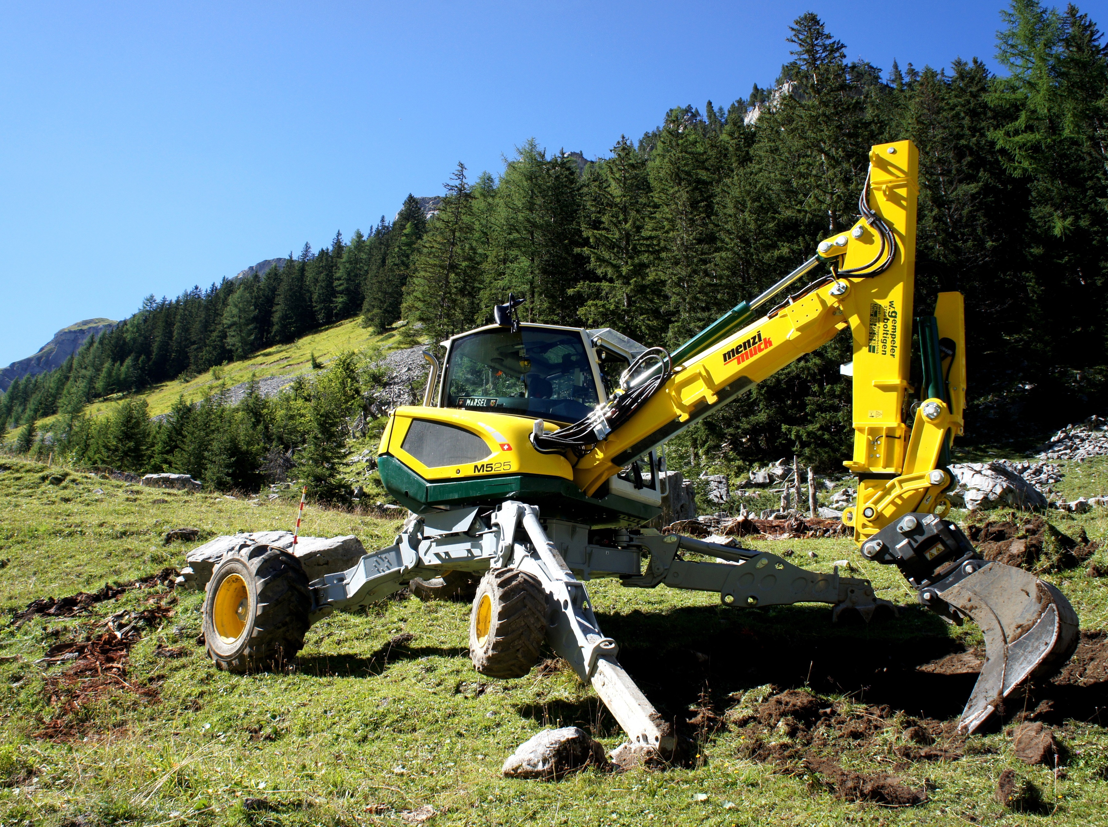 Menzi Muck M525 excavator on a grassy slope HD Wallpaper