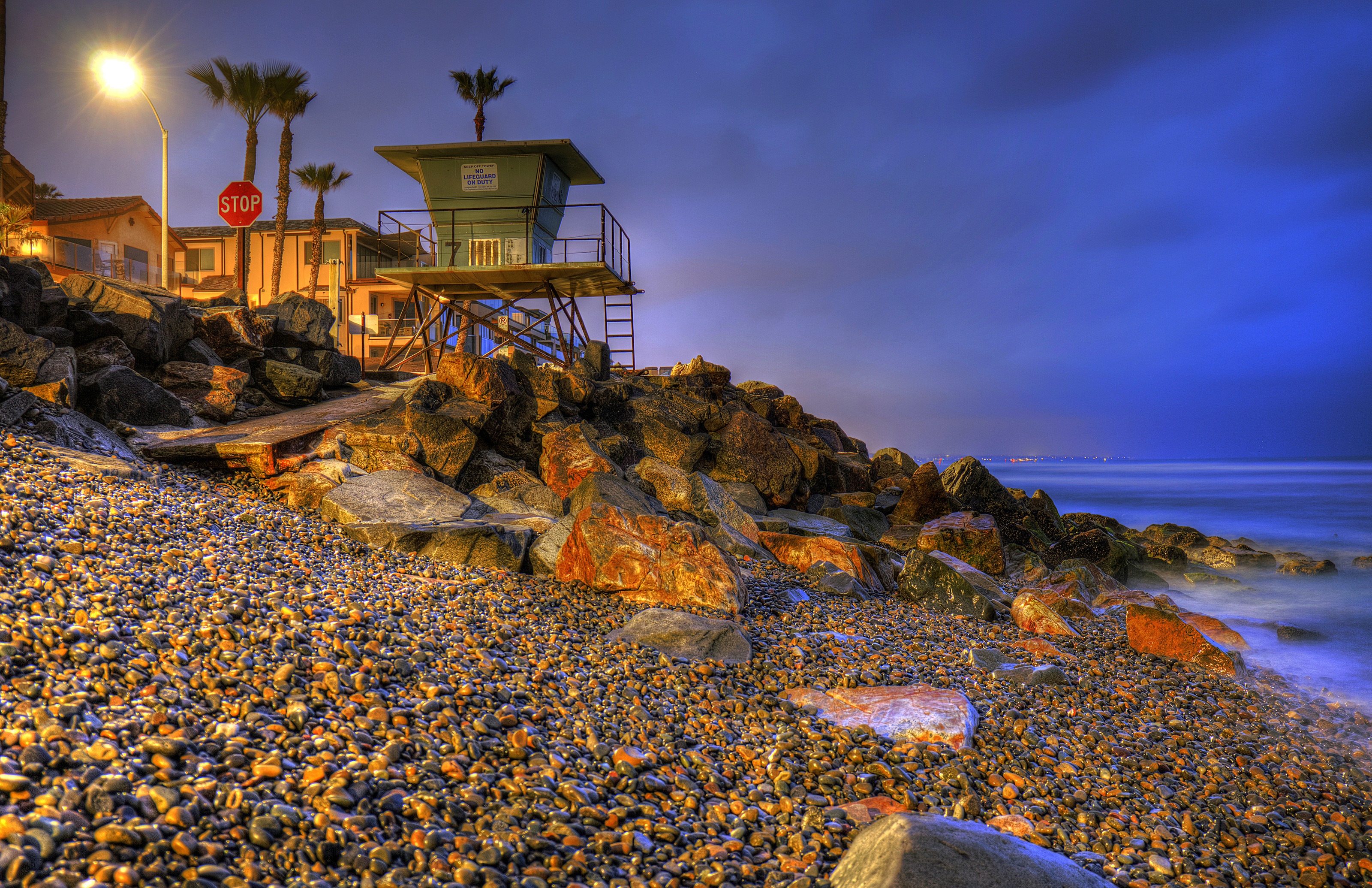 Lifeguard tower on a rocky beach at dusk in Oceanside, California HD Wallpaper