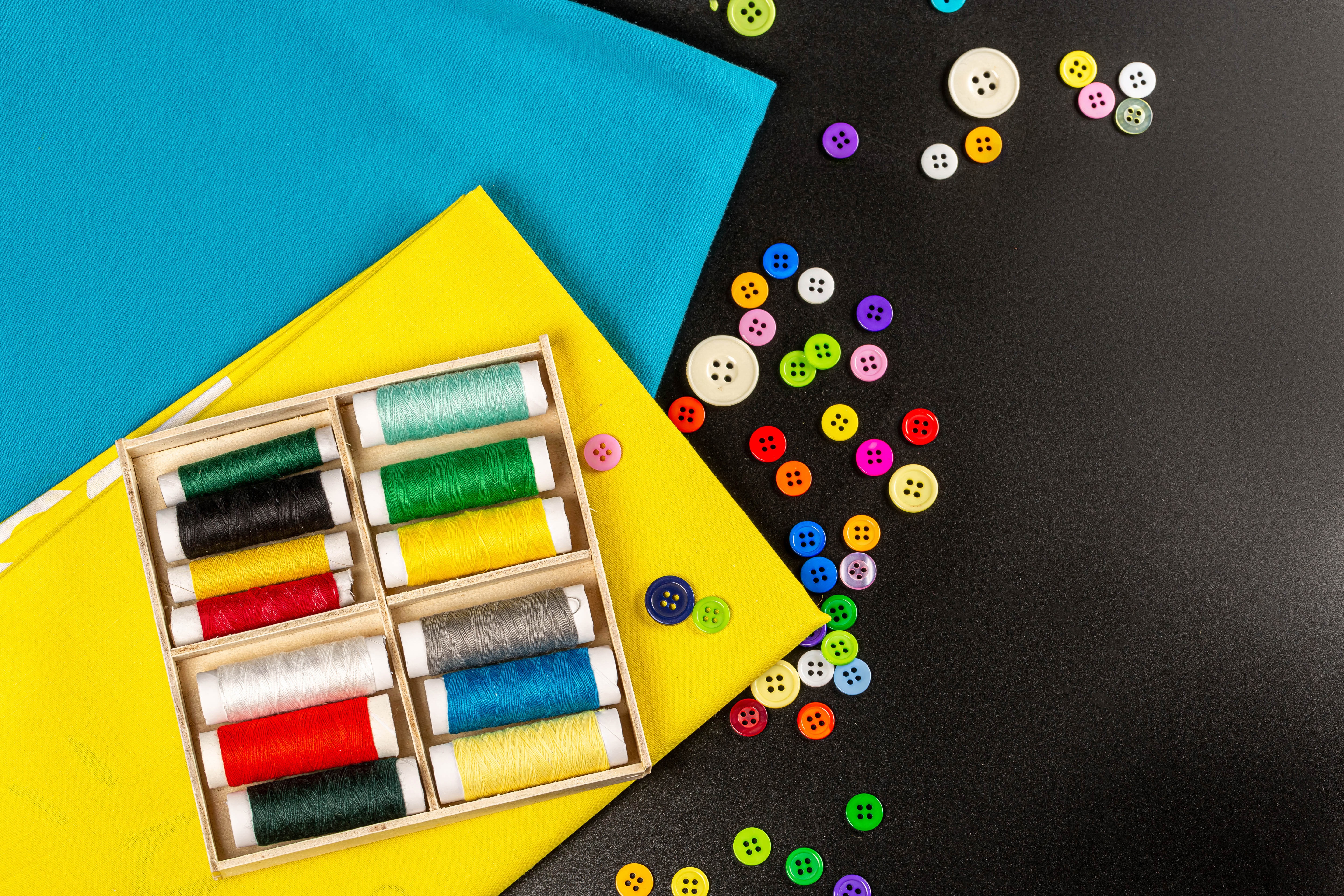 Sewing supplies with threads and buttons on gray background HD Wallpaper