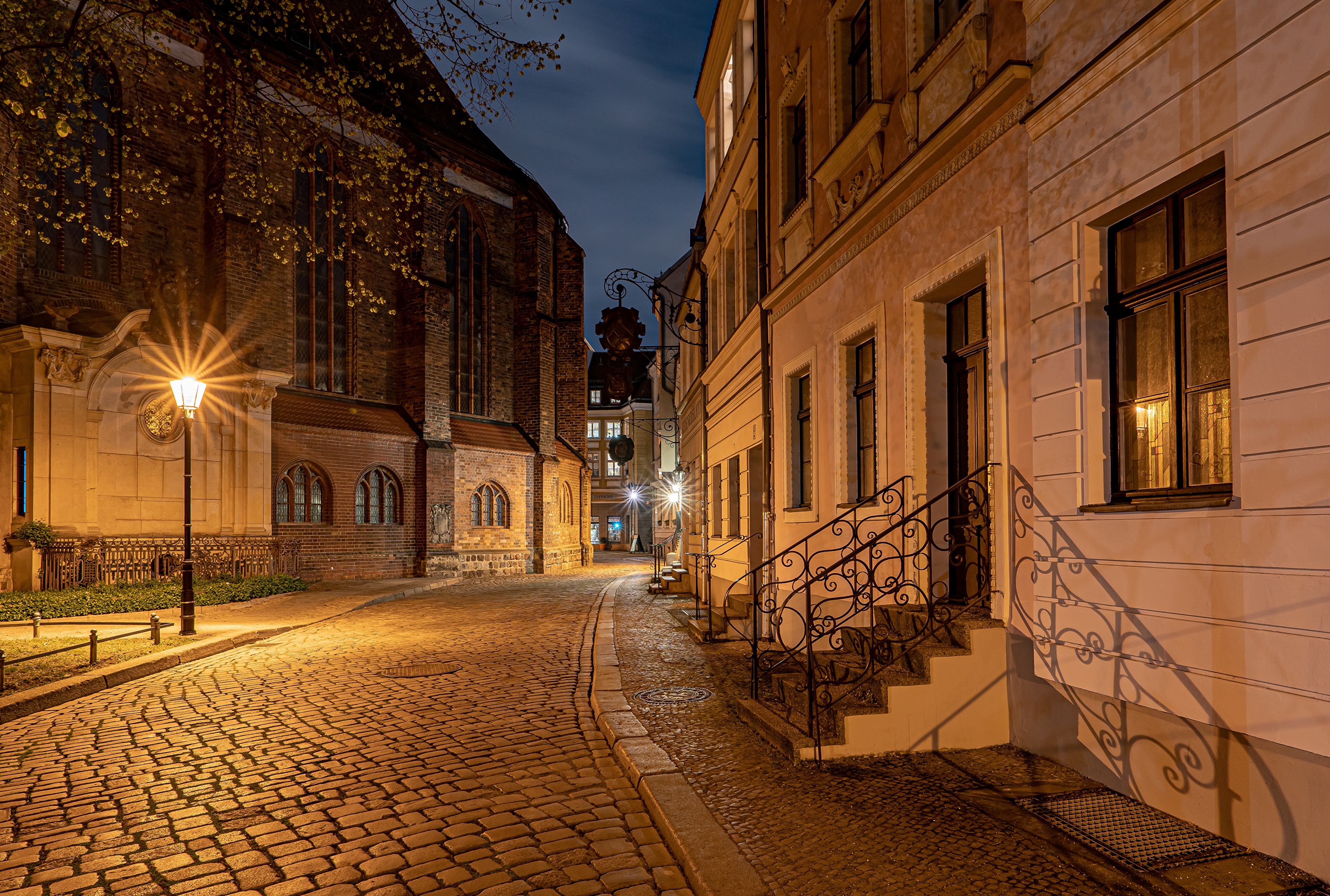 Cobblestone street with church and buildings at night HD Wallpaper