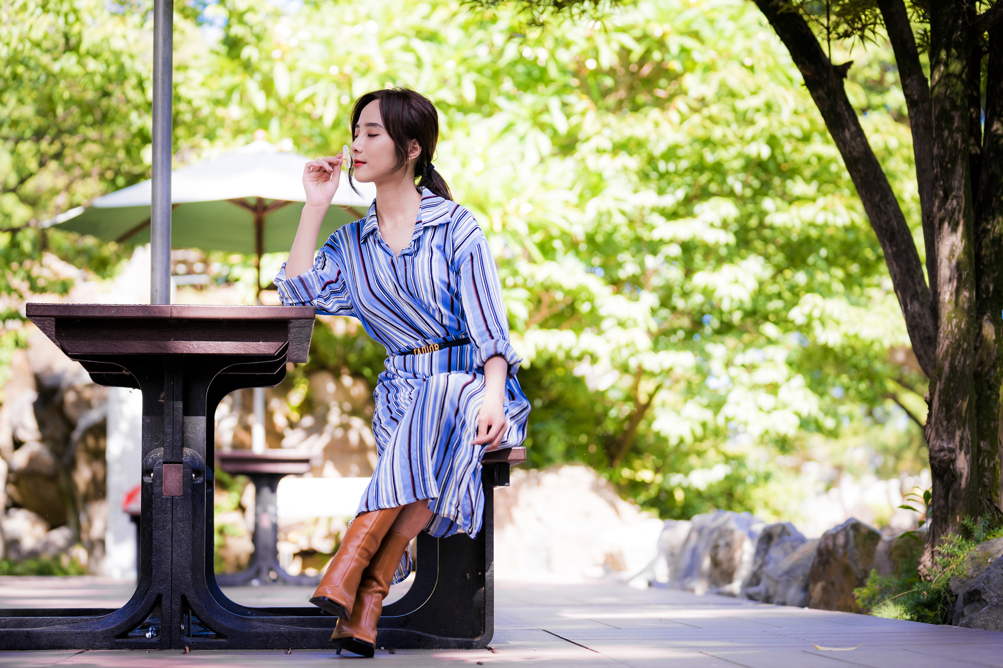 Asian woman sitting at a table outdoors HD Wallpaper