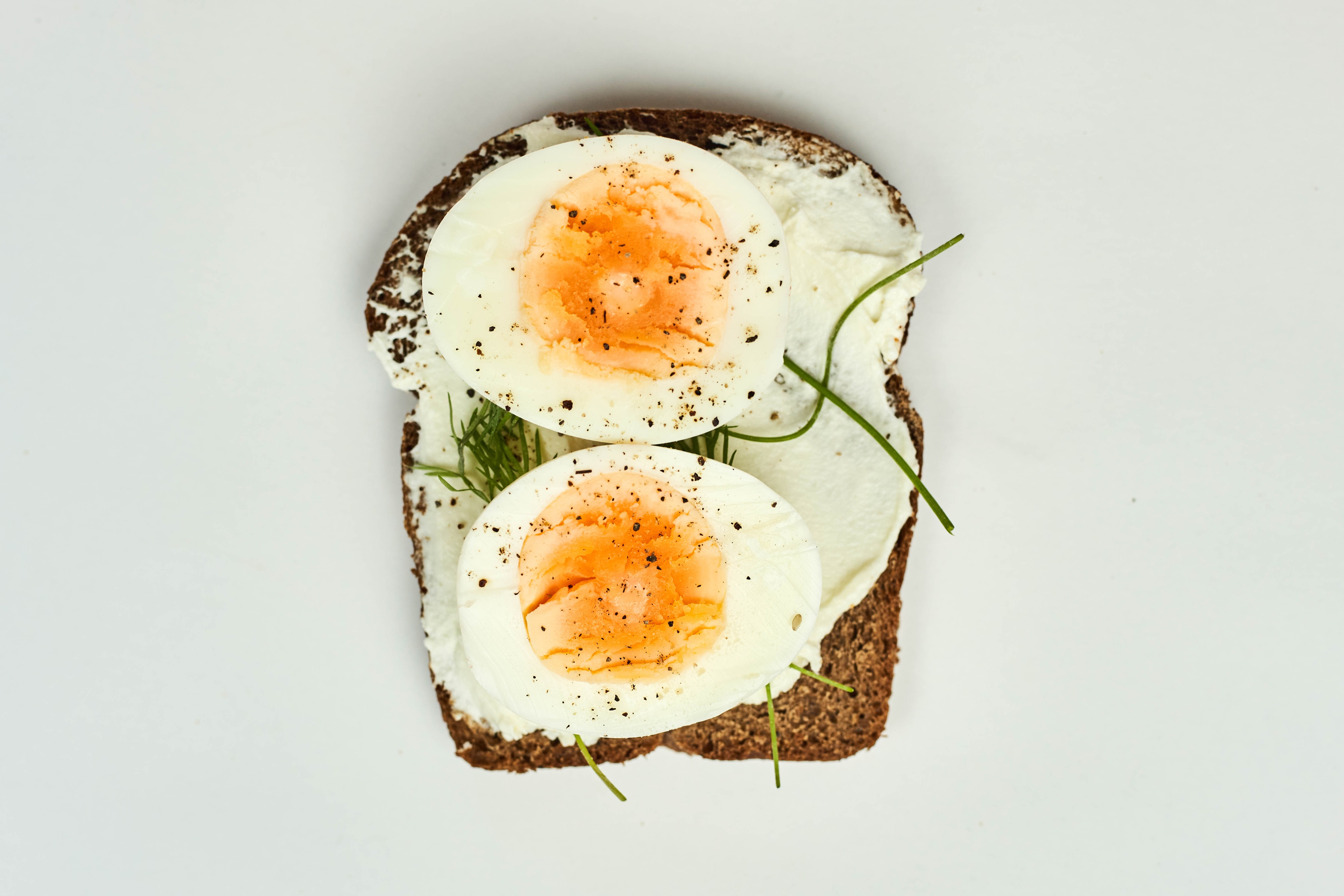 Open-faced sandwich with cream cheese, hard-boiled eggs, and herbs HD Wallpaper