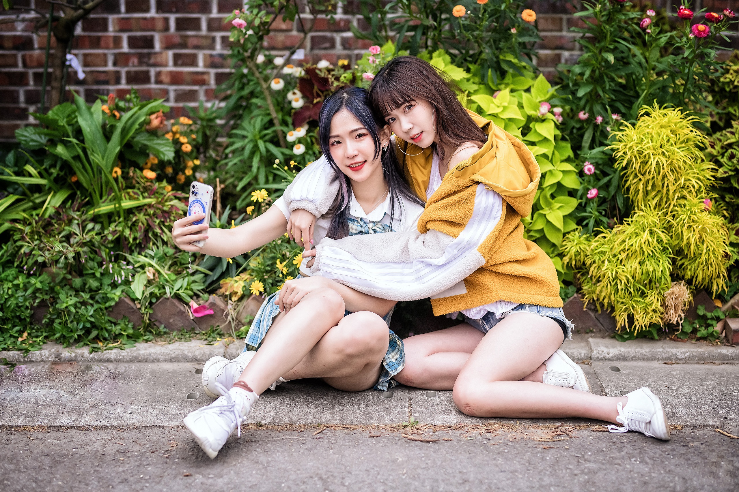 Two Asian women taking a selfie in front of flowers HD Wallpaper