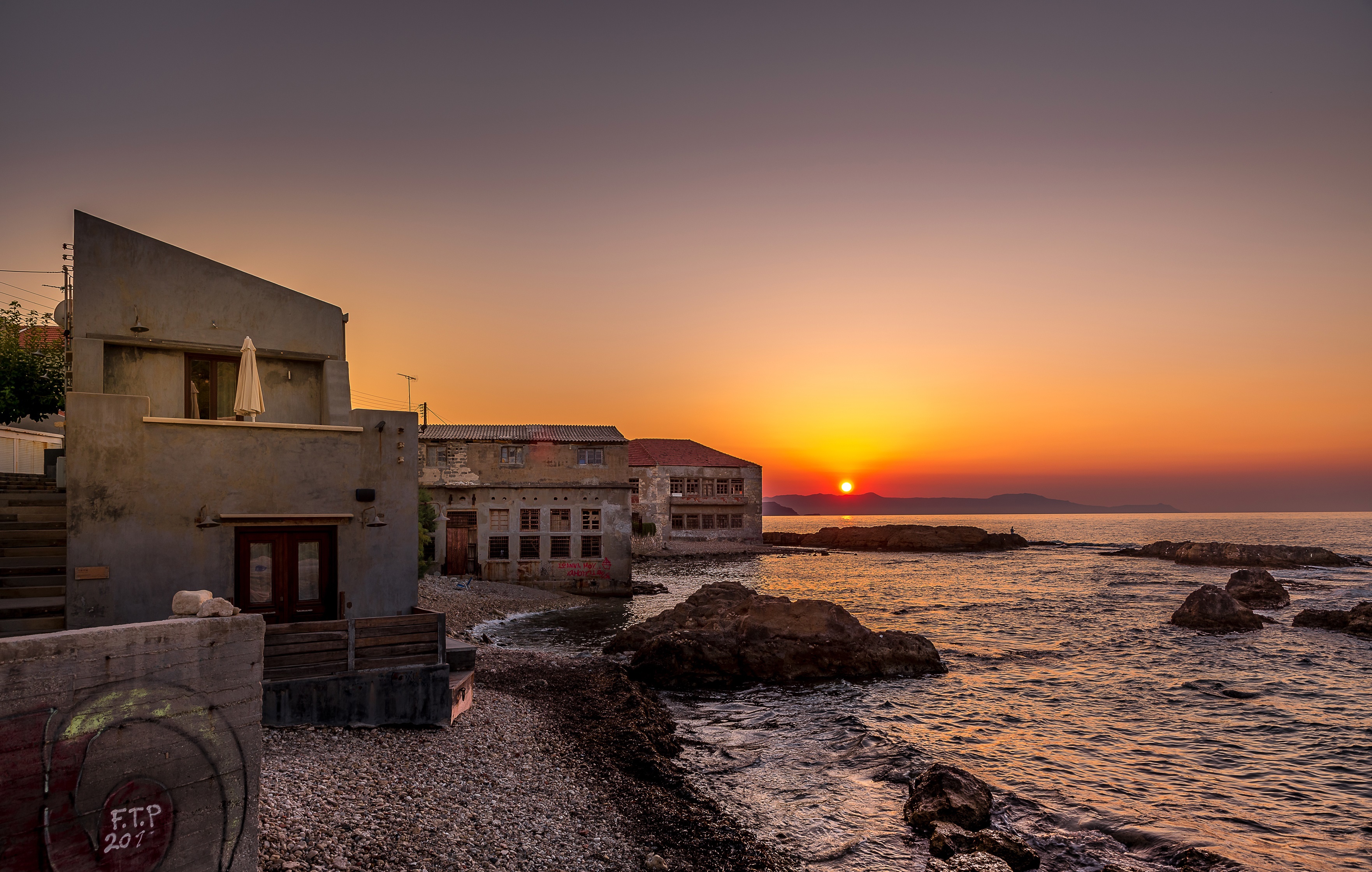 Sunset over the coast of Chania, Crete with houses and waves HD Wallpaper